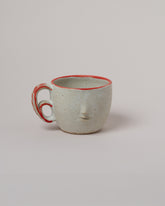 Rami Kim Red Swipe Accent Face Mug With Double Loop Handle on light color background.