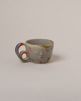 Rami Kim Yellow Dream Face Mug With Double Loop Handle on light color background.