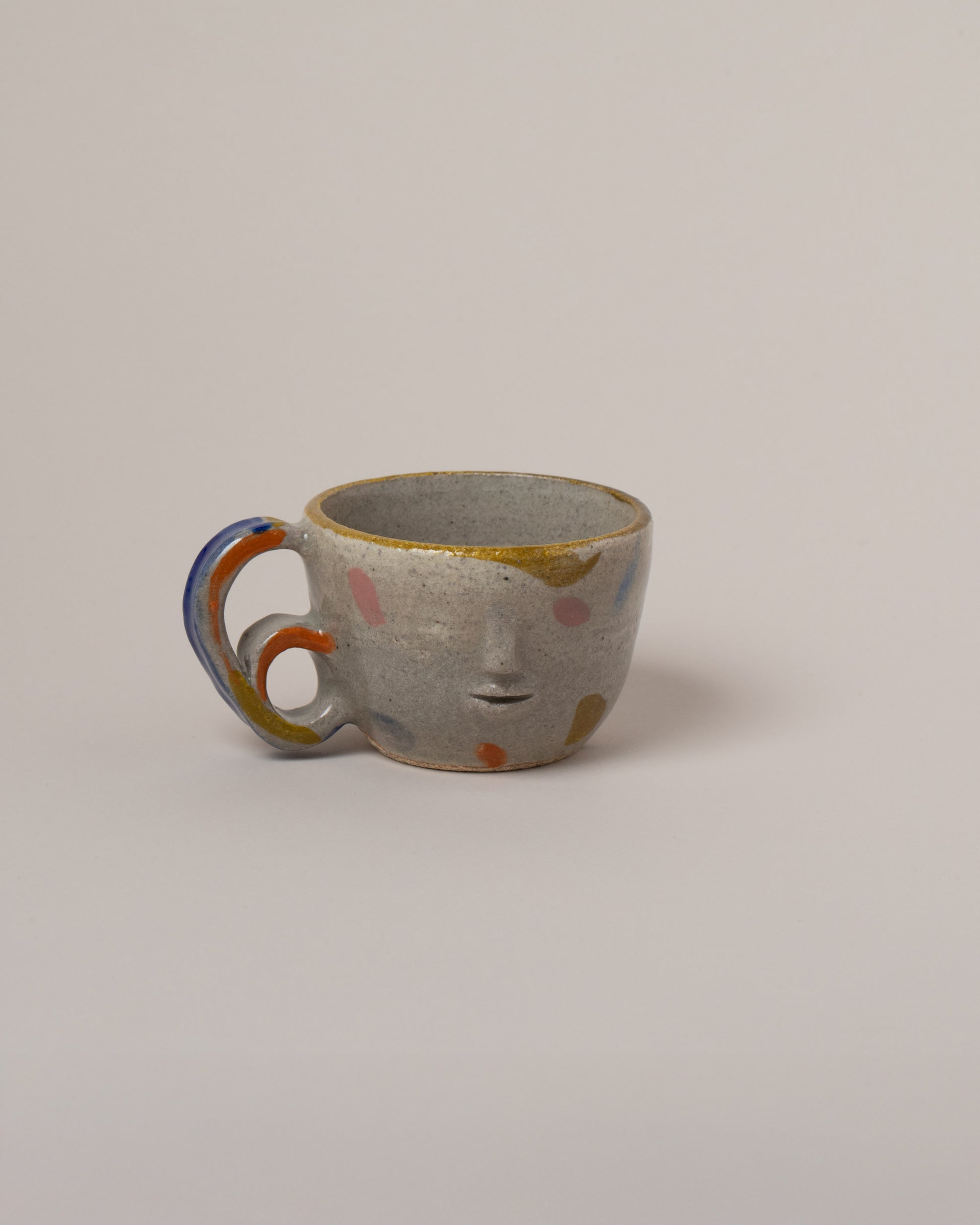 Rami Kim Yellow Dream Face Mug With Double Loop Handle on light color background.