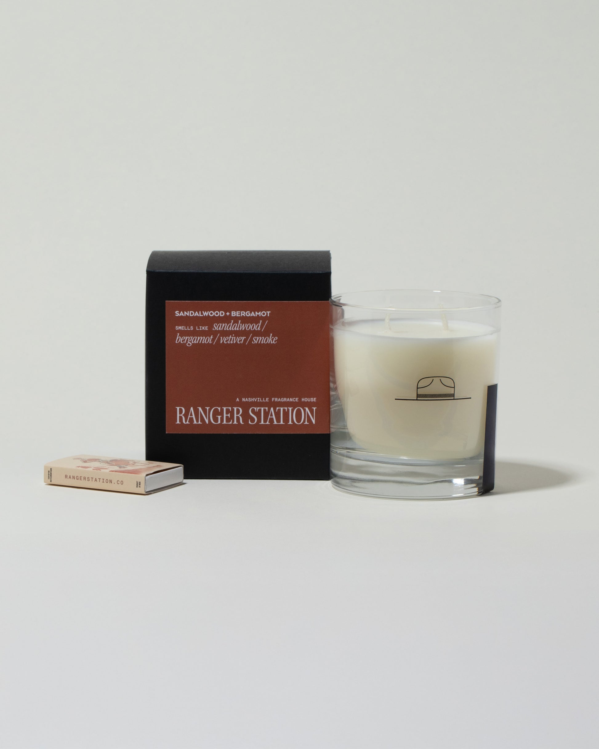 Ranger Station Sandalwood & Bergamot Candle with matchbox on light color background.