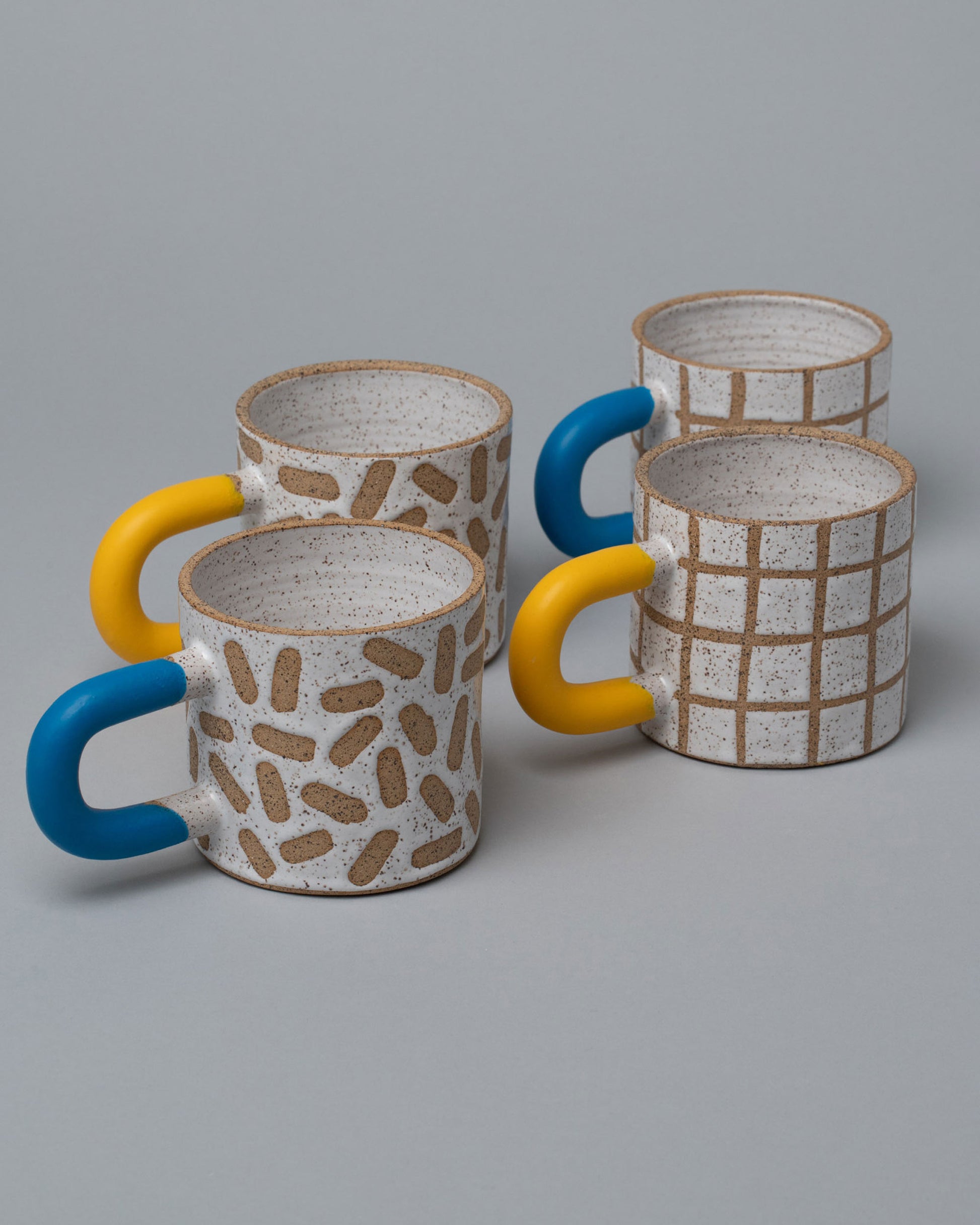Closeup view of the Recreation Center Mugs Set, including Blue and Yellow Mark Mugs and Blue and Yellow Grid Mugs on light color background,