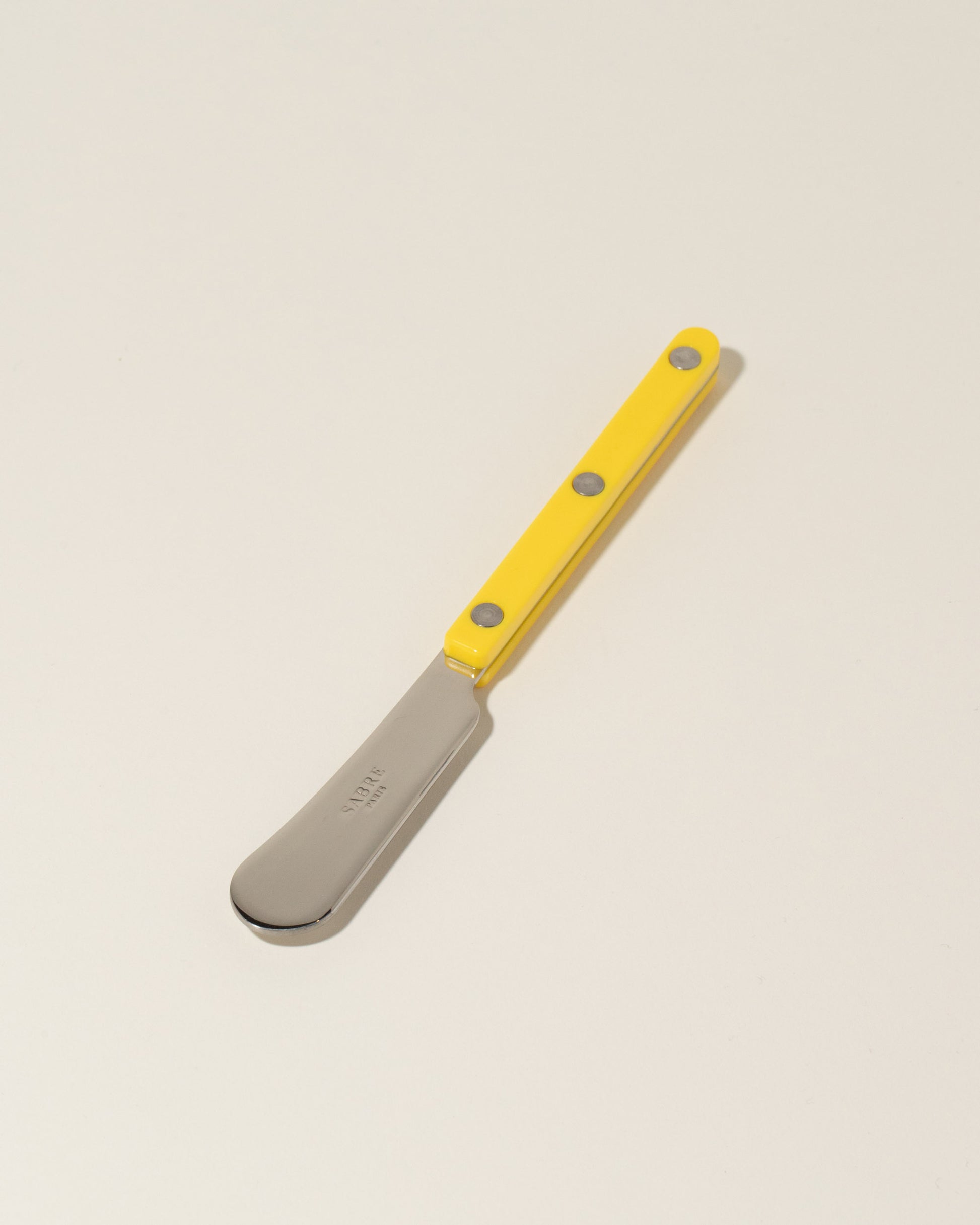 Sabre Paris Yellow Butter Spreader on light color background.