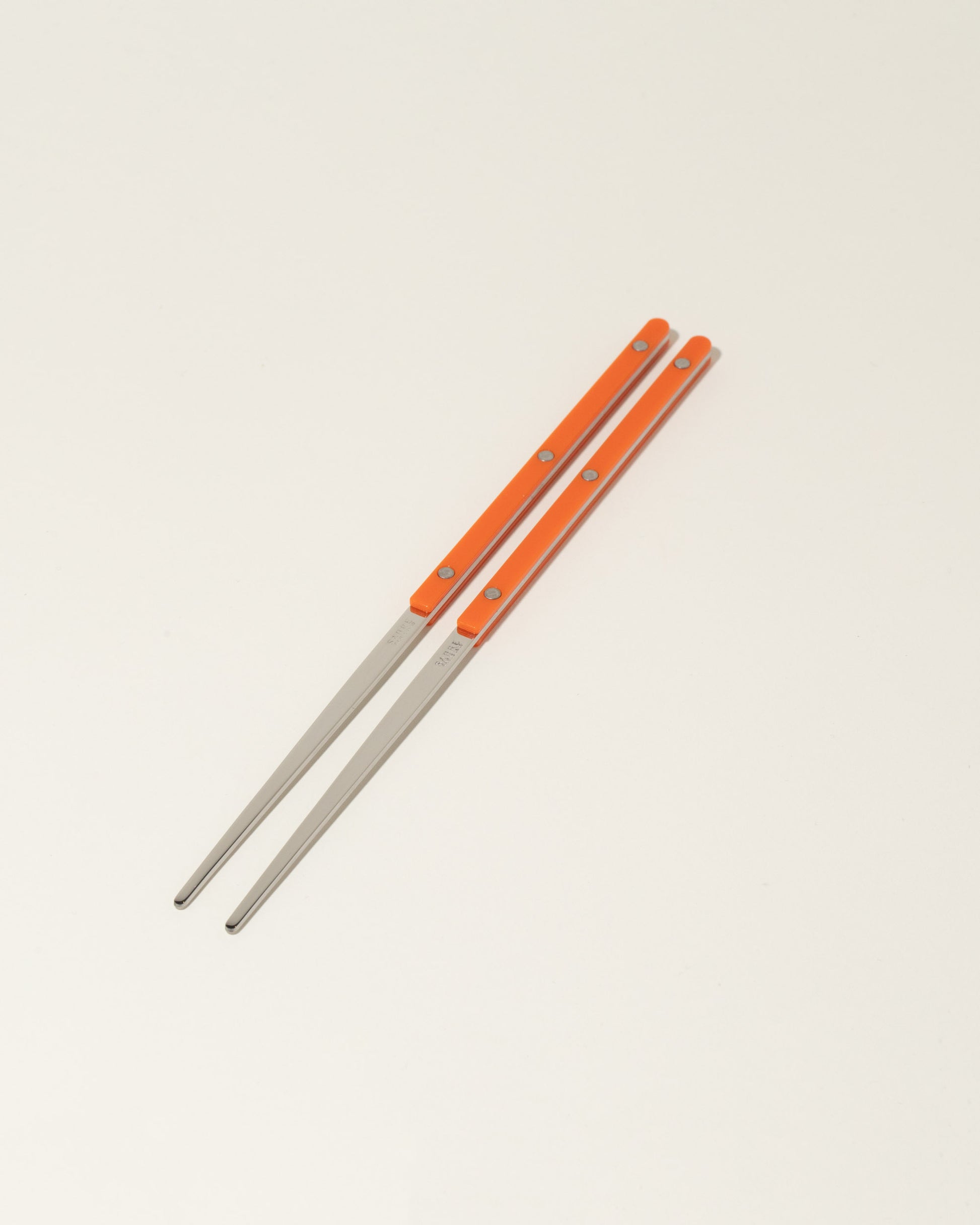 Sabre Paris Orange Chopsticks on light color background.