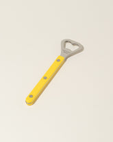 Sabre Paris Yellow Bottle Opener on light color background.