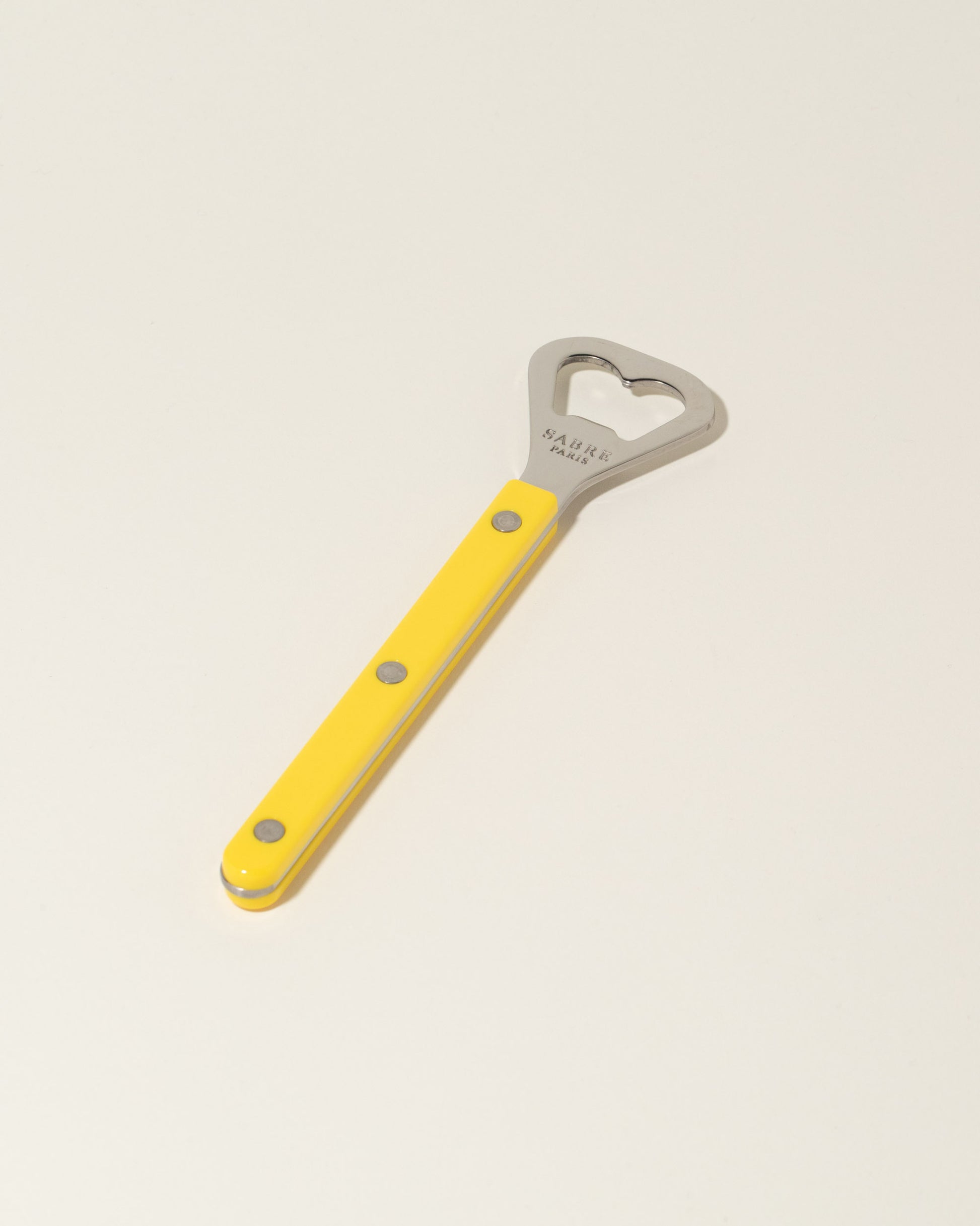 Sabre Paris Yellow Bottle Opener on light color background.