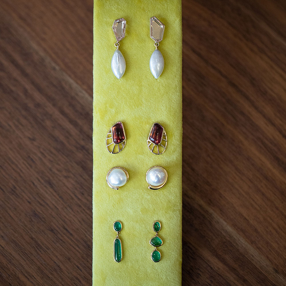 Closeup view mixed style one-of-a-kind earrings including the Tricopilia Earrings, Lycaste Earrings, Nereus Earrings and Eternal Life Earrings on a chartreuse green earring tray.