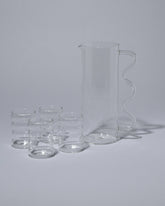 Sophie Lou Jacobsen Drinks are Served Set, including the Clear with Clear Handle Wave Pitcher and Small Clear Ripple Cups, on light color background.