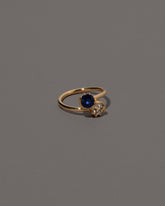 View from the side of the Sapphire & Diamond Sun & Moon Union Ring on light color background.