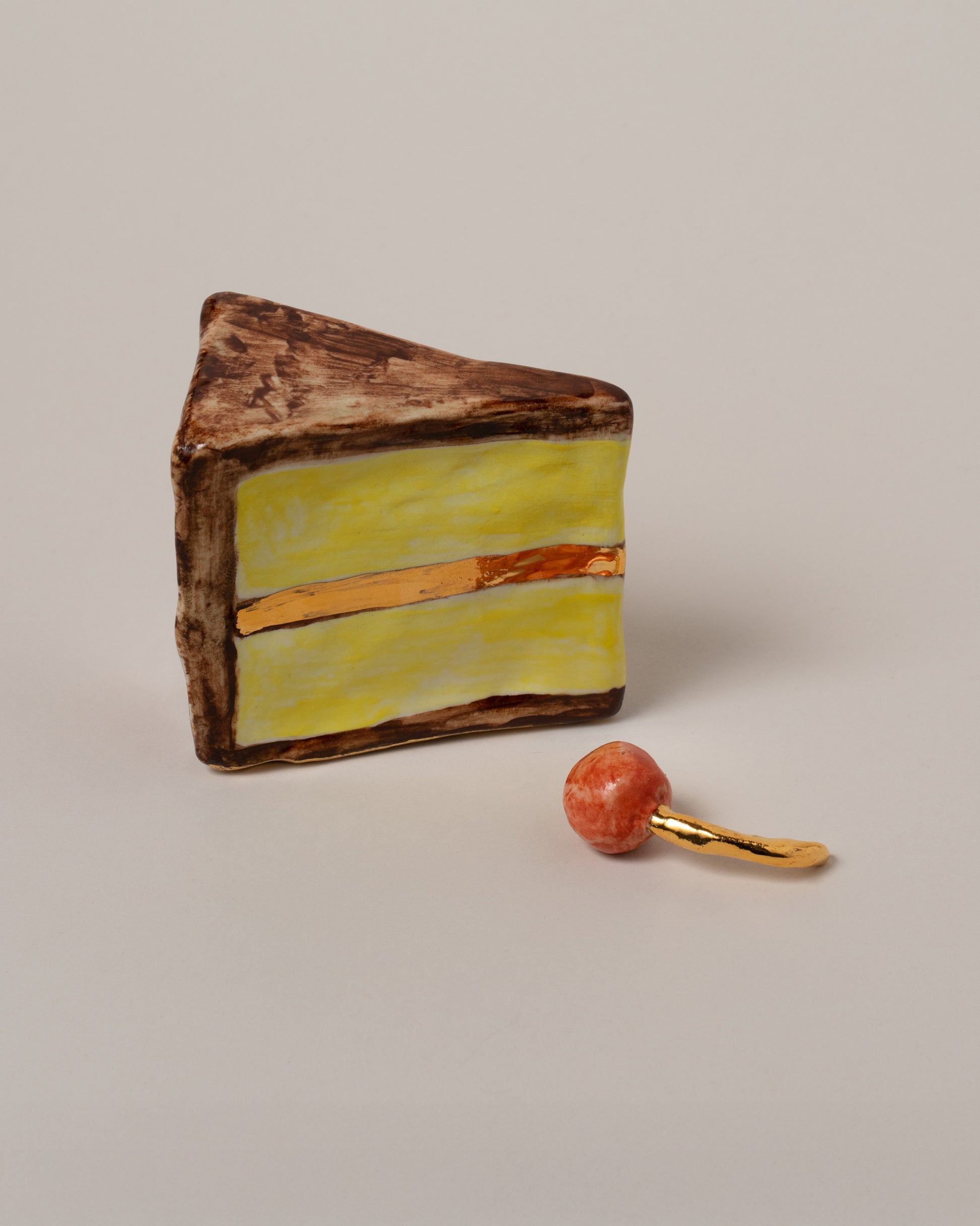 Closeup details of the Suzanne Sullivan Piece Of Cake & Cherry Not On Top on light color background.