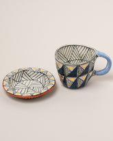 Detail view of the Suzanne Sullivan One A Long Story Short Espresso Cup & Saucer on light color background.