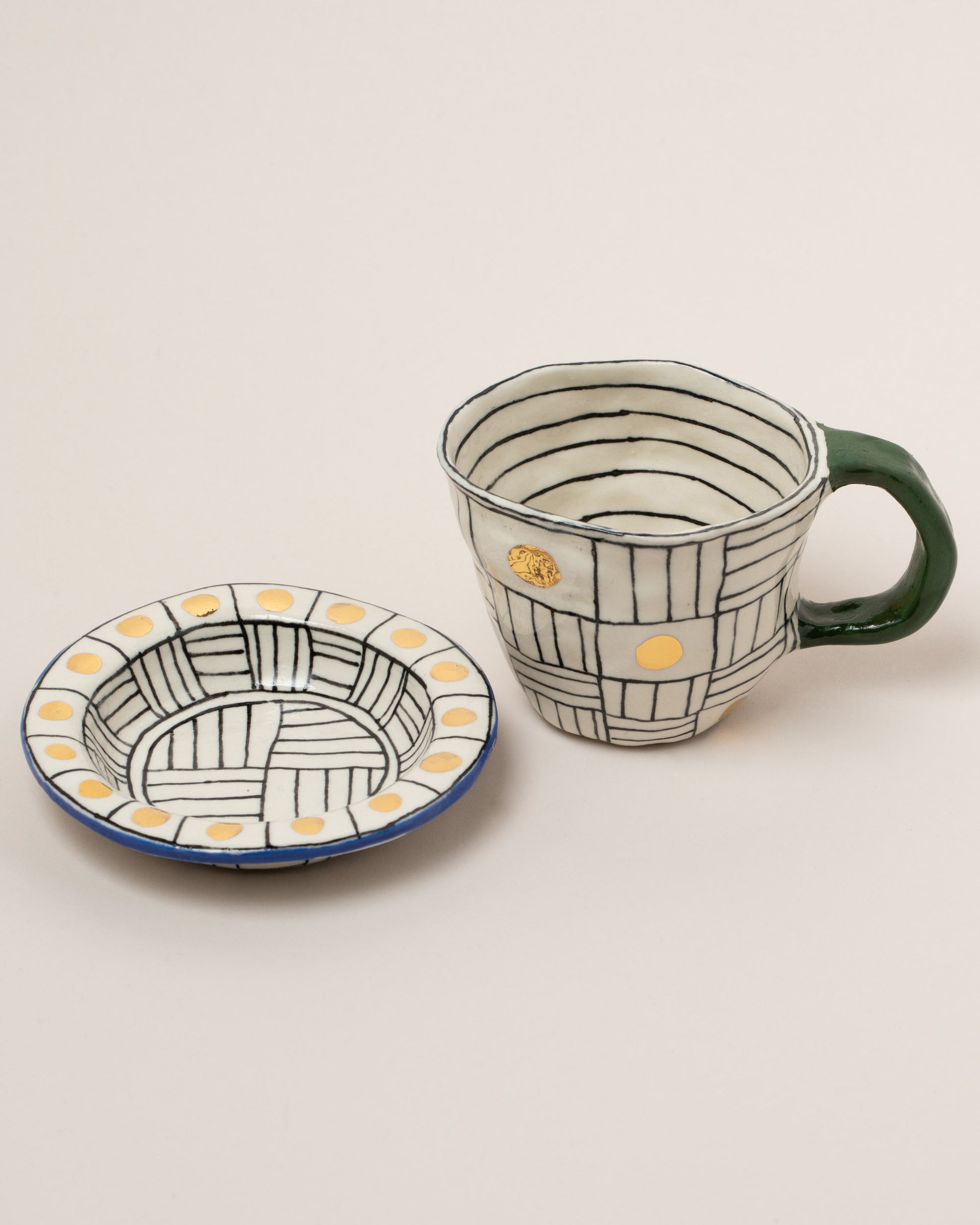 Detail view of the Suzanne Sullivan Two A Long Story Short Espresso Cup & Saucer on light color background.