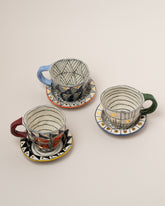 Suzanne Sullivan Two A Long Story Short Espresso Cup & Saucer sets on light color background.