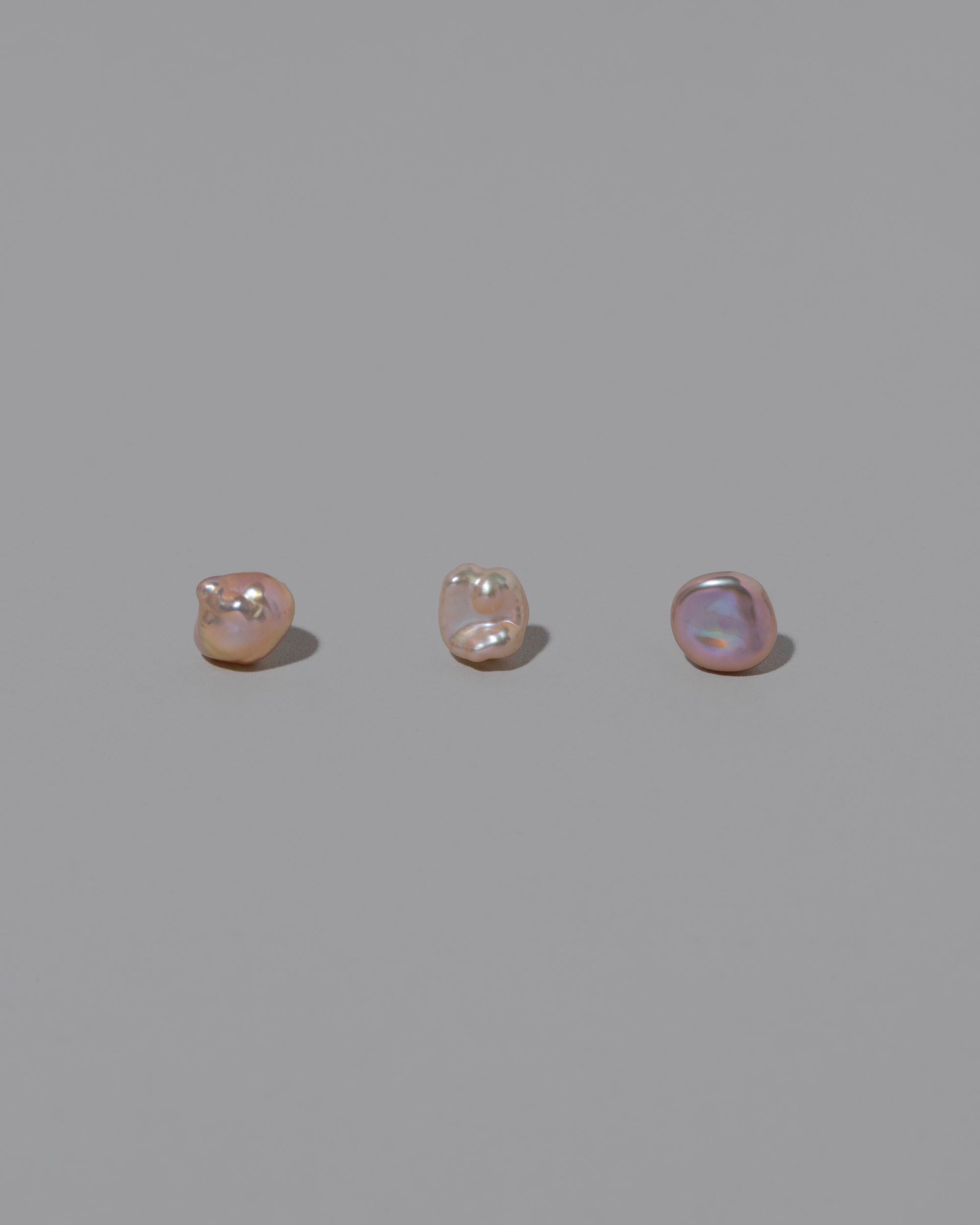 Group of Blush Lagniappe Pearl Stud Earring Singles on light color background.