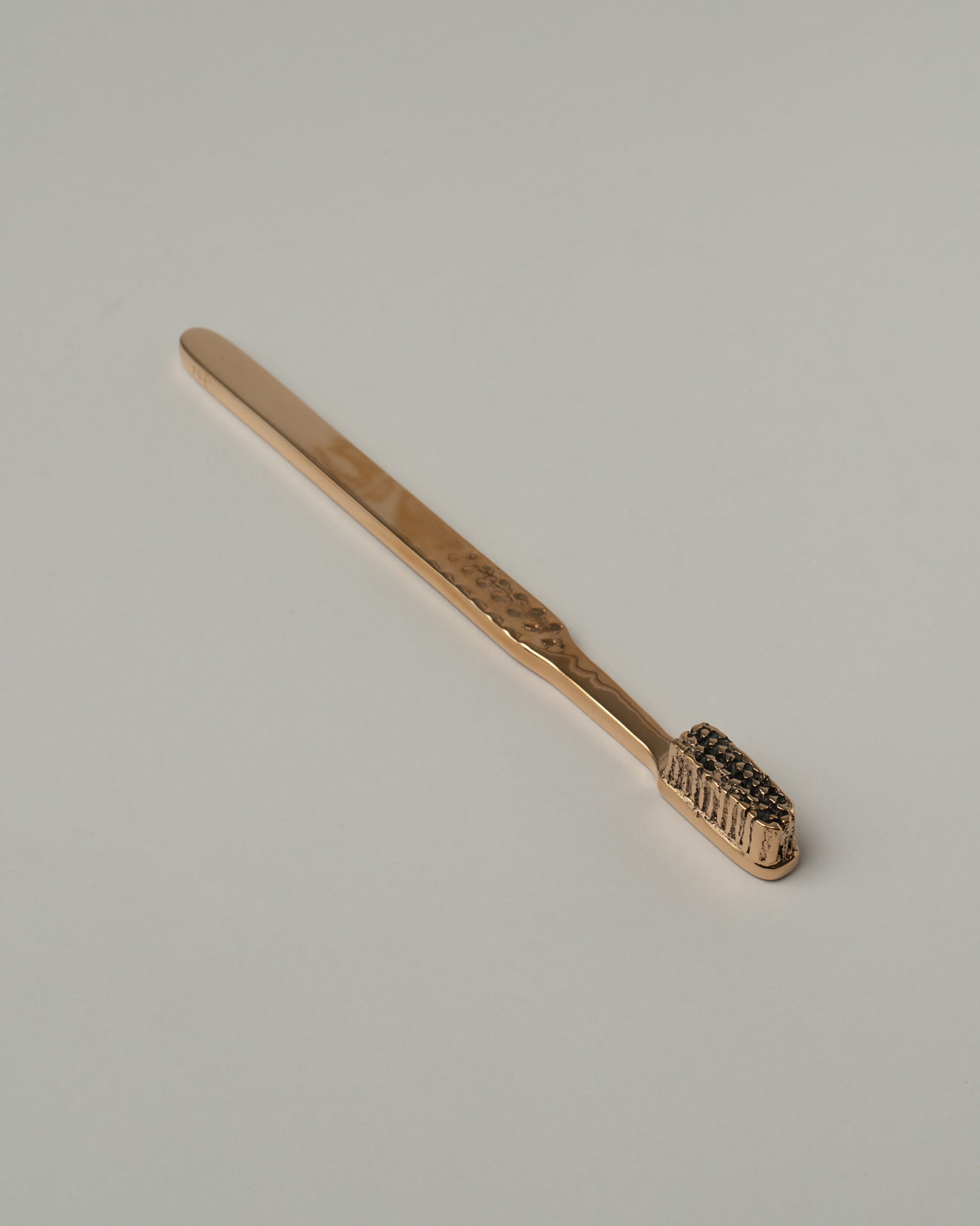 Pearce Objects Cast Bronze Toothbrush on light color background.