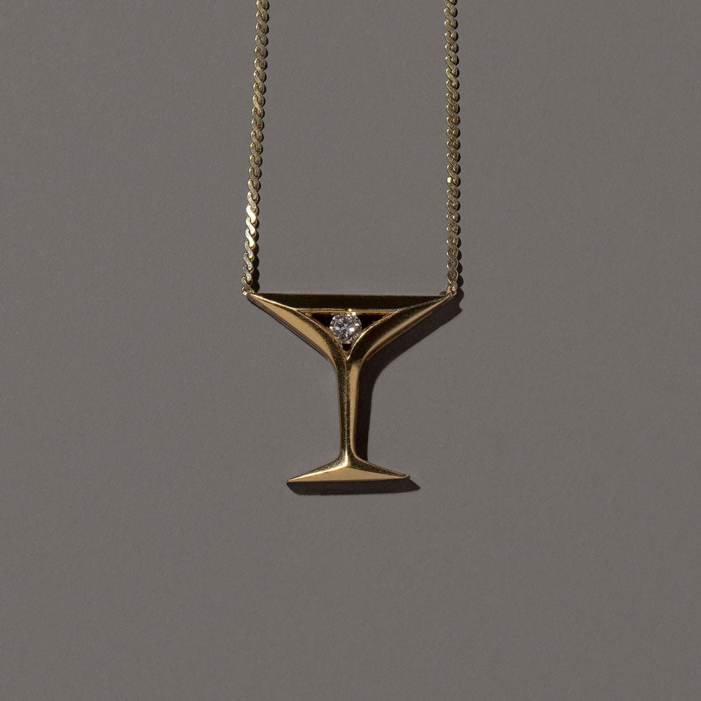 product_details::Closeup details of the Martini Pendant Necklace on grey color background.