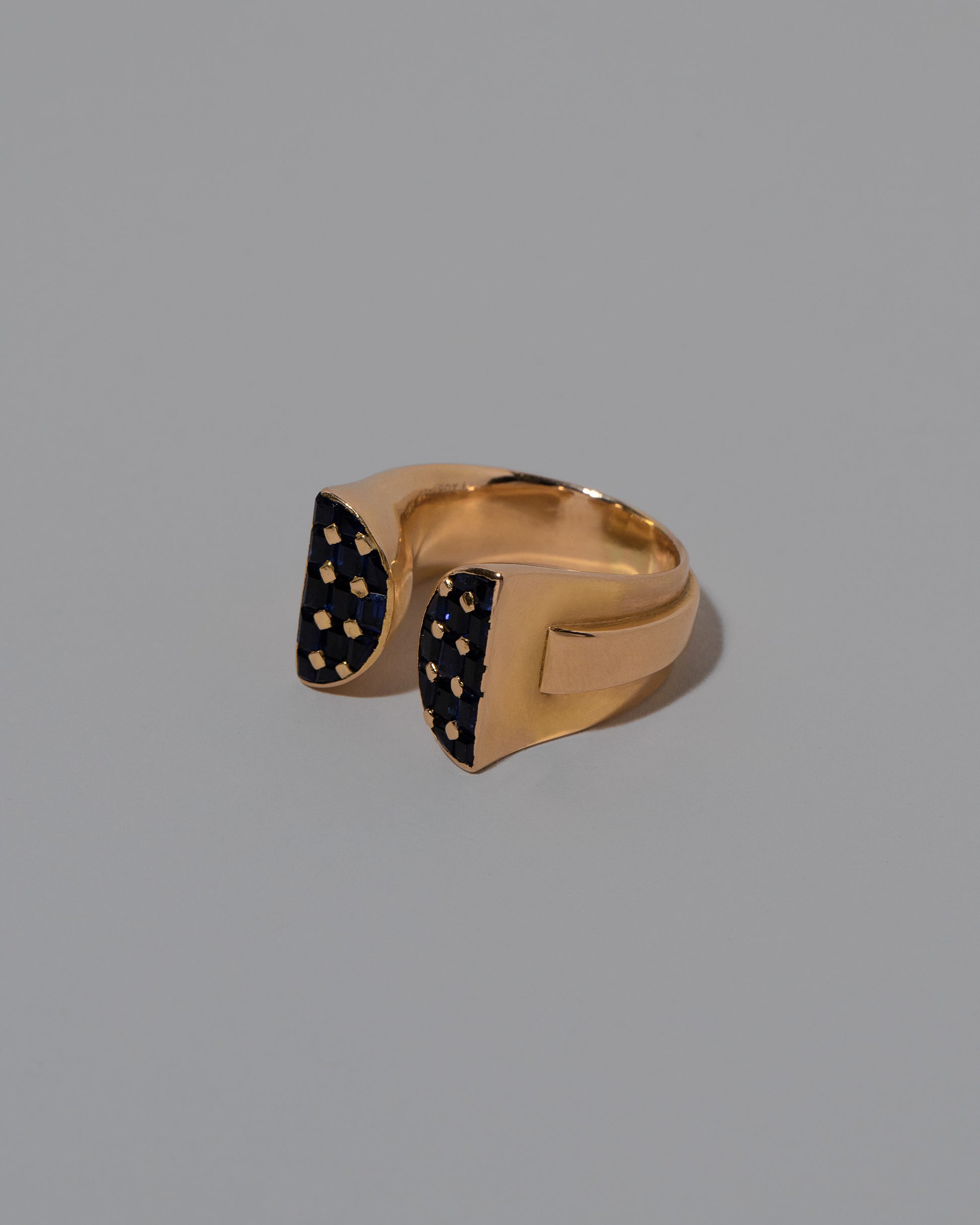 View from the side of the Vintage Mauboussin Paris Blue Sapphire Bow Ring on light color background.