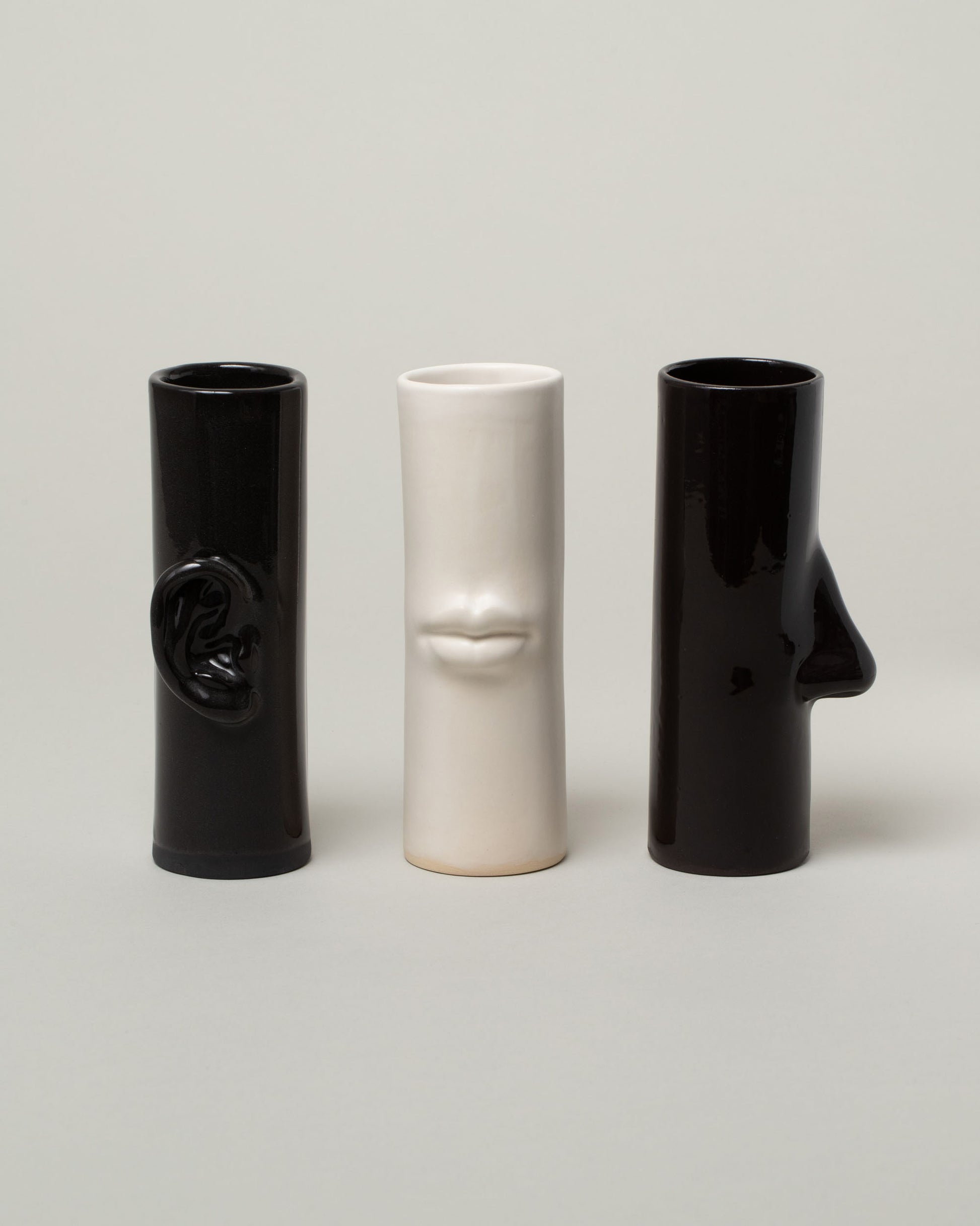 Group of Bonam Kim Black Ear Pillar Vase, White Lip Pillar Vase, and Black Nose Pillar Vase on light color background.