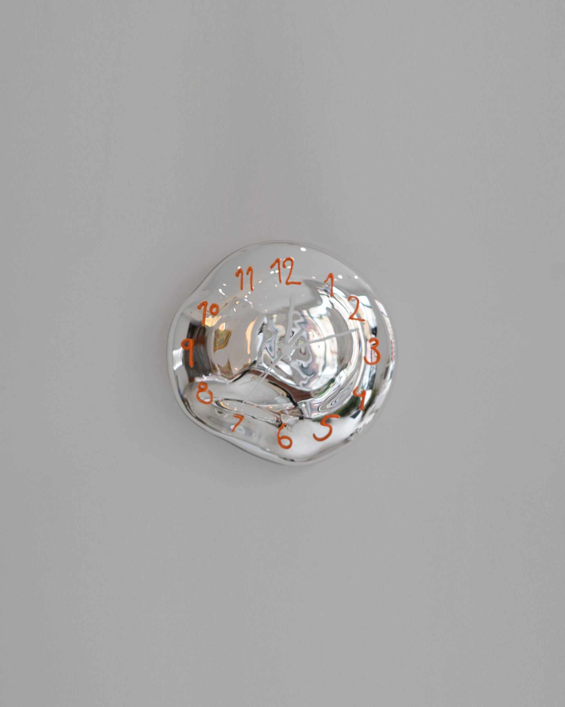 Silje Lindrup White Hands Two Orange Glass Wall Clock on light color background.