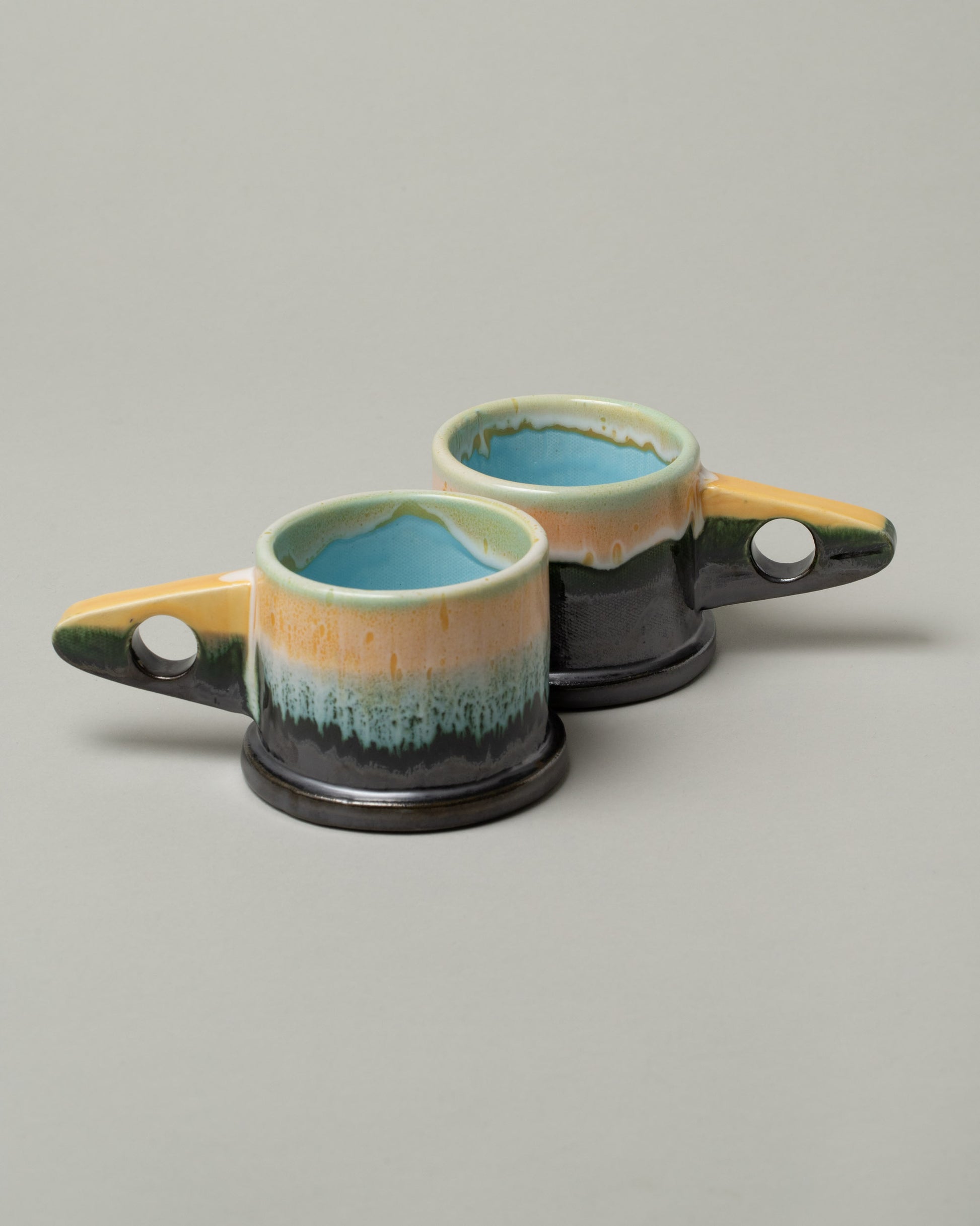 Group of Echo Park Pottery by Peter Shire Gunmetal Double Dip Mugs on light color background.