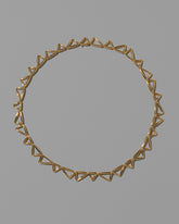 Gold Flexure Necklace on light color background.