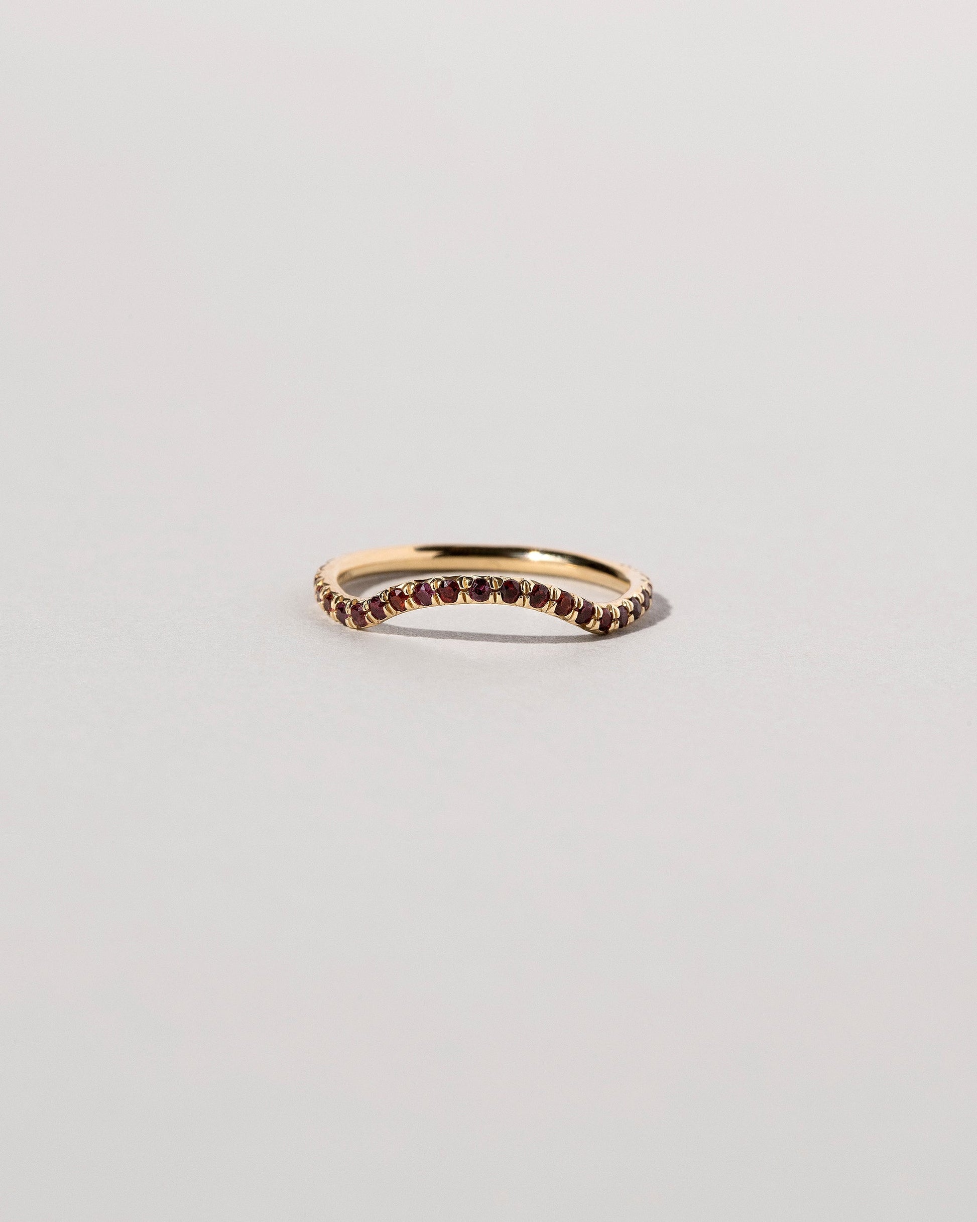 Gold Garnet Pavé Mini Curve Band on light color background.