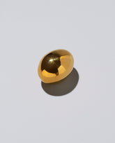 View from the side of the Carl Auböck Brass Egg Paperweight on light color background.
