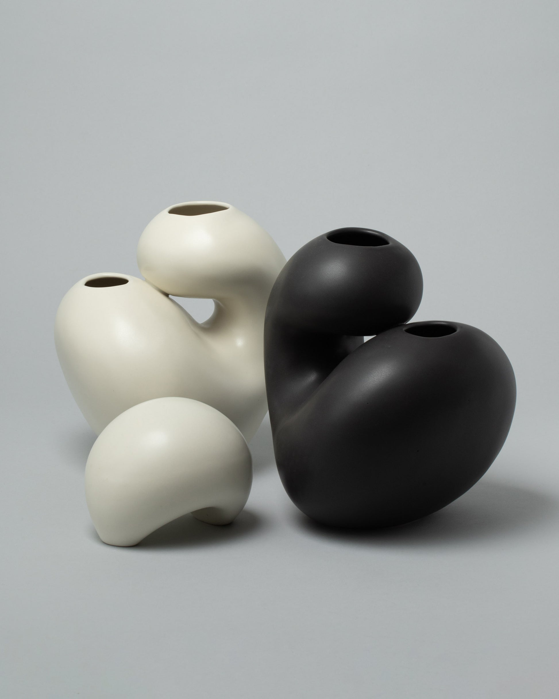 Group photo of Dust and Form Being Form, Ivory Vita Vessel, and Charcoal Vita Vessel on light colored background.
