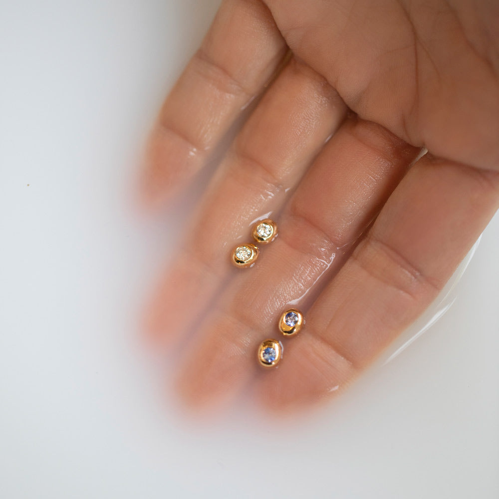 product_details::Yellow Gold Bicolor Blue Sapphire Level Stud Earrings and Yellow Gold Diamond Level Stud Earrings in hand.