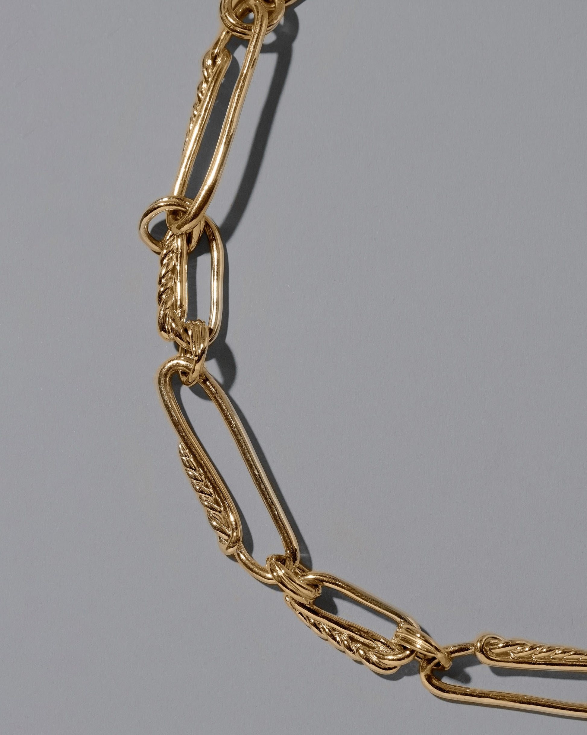 Closeup details of the CRZM 22k Gold Ophiolite Necklace on light color background.