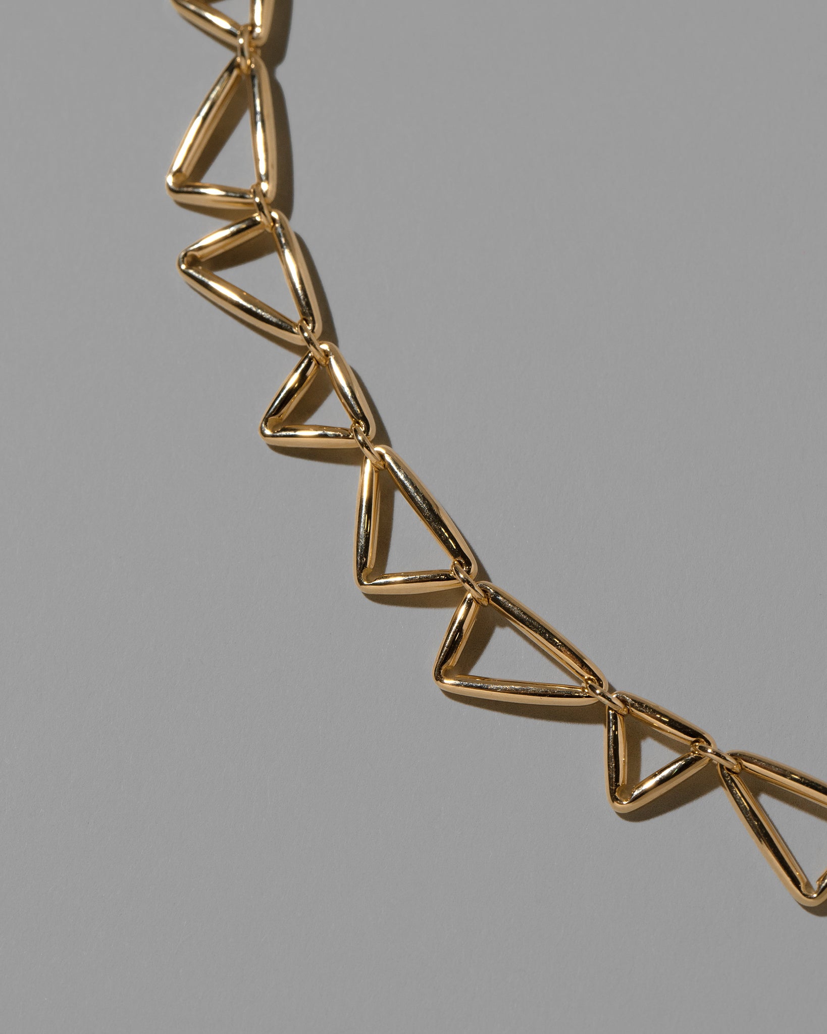 Closeup details of the Gold Flexure Necklace on light color background.