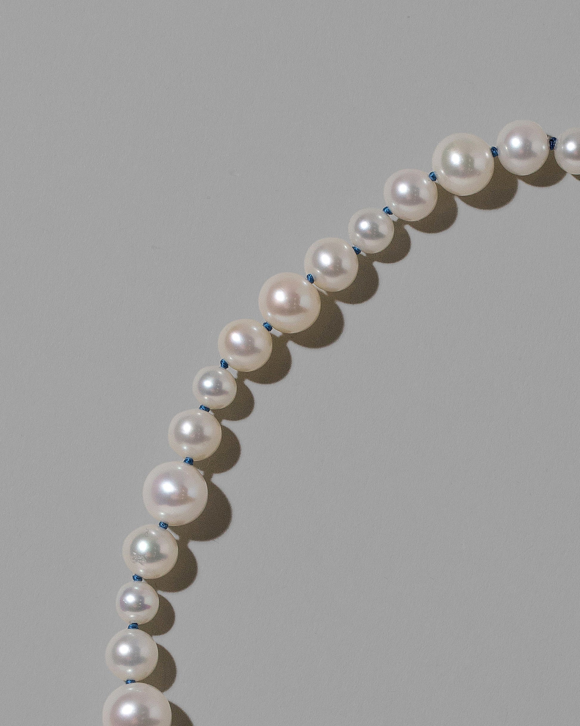 Closeup details of the Indigo Blue Thread Bubble Pearl Bracelet on light color background.