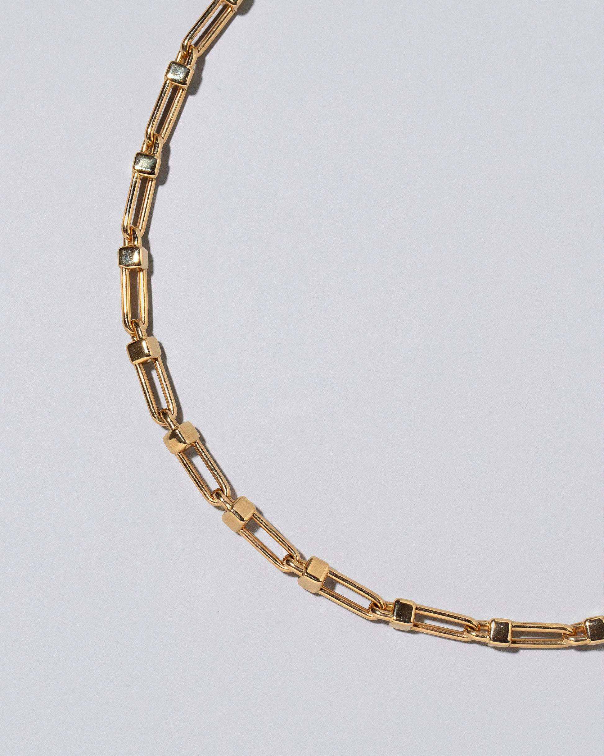 Closeup detail of the Lightweight Half Loop Link Necklace on light color background.