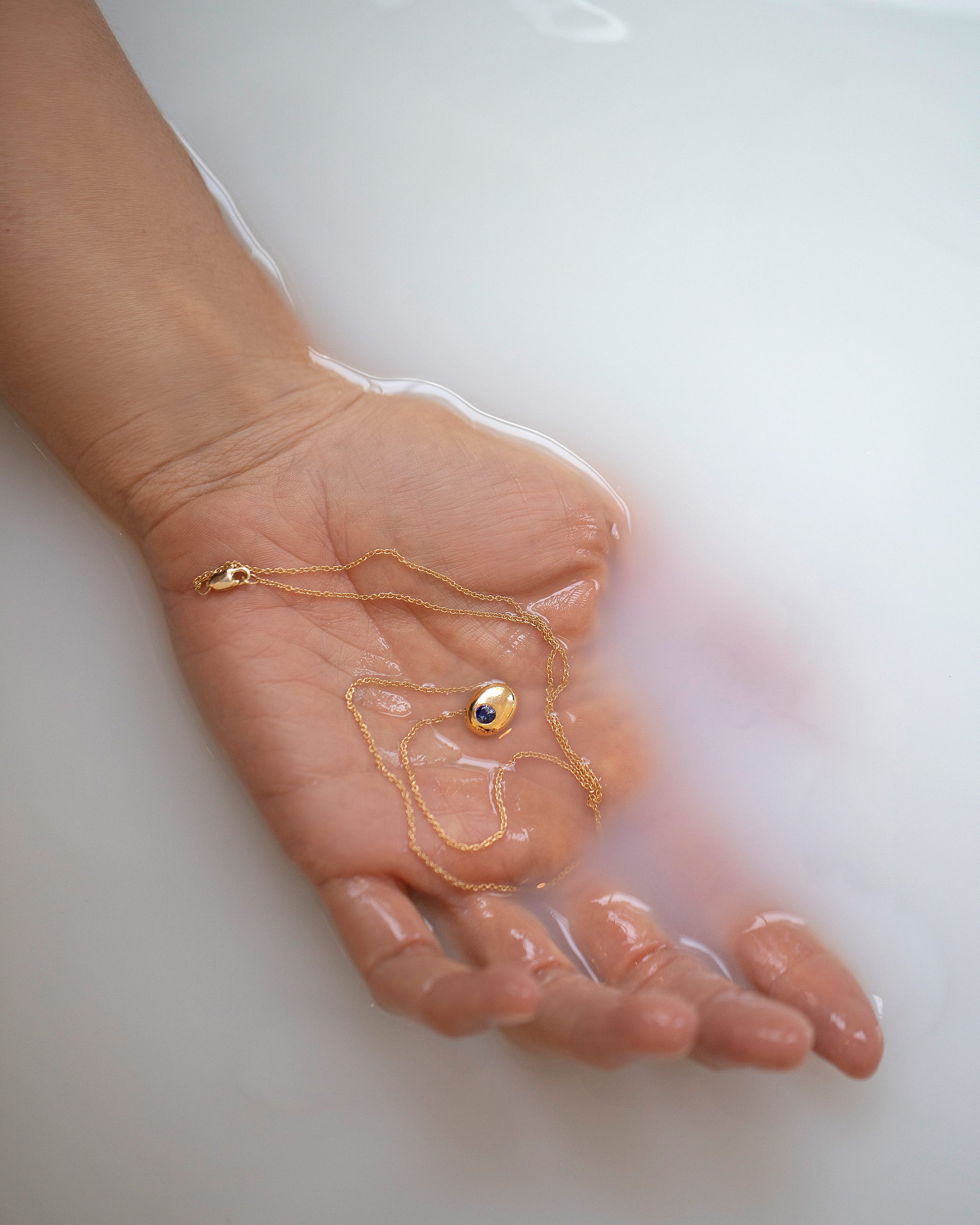 Yellow Gold Bicolor Blue Sapphire Level Necklace in hand.