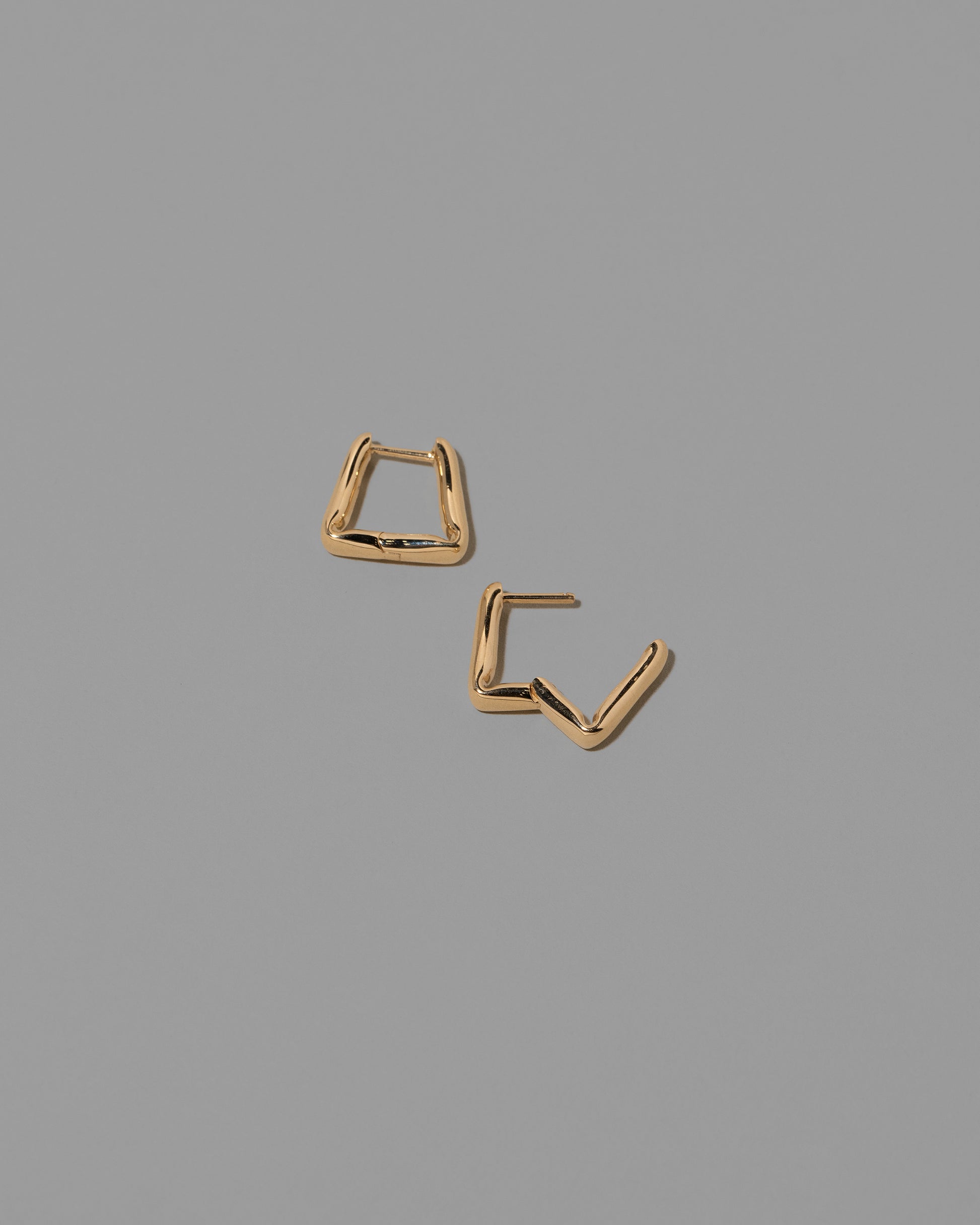 Detail view of the Gold Kink Hoop Earrings on light color background.