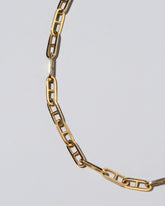 Closeup detail of the Lightweight Anchor Loop Chain Necklace on light color background.