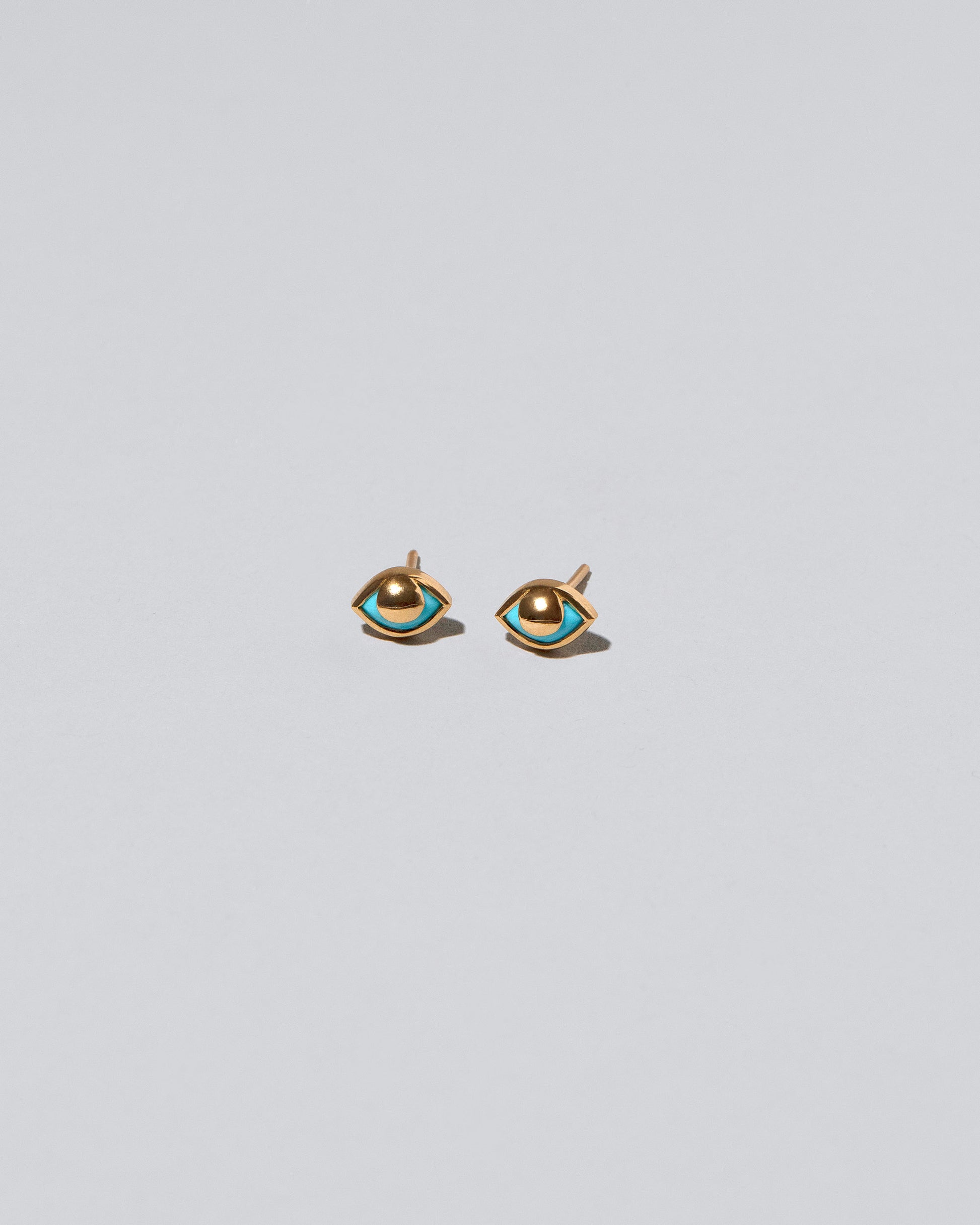 Gold Eye See You Stud Earrings on light color background.