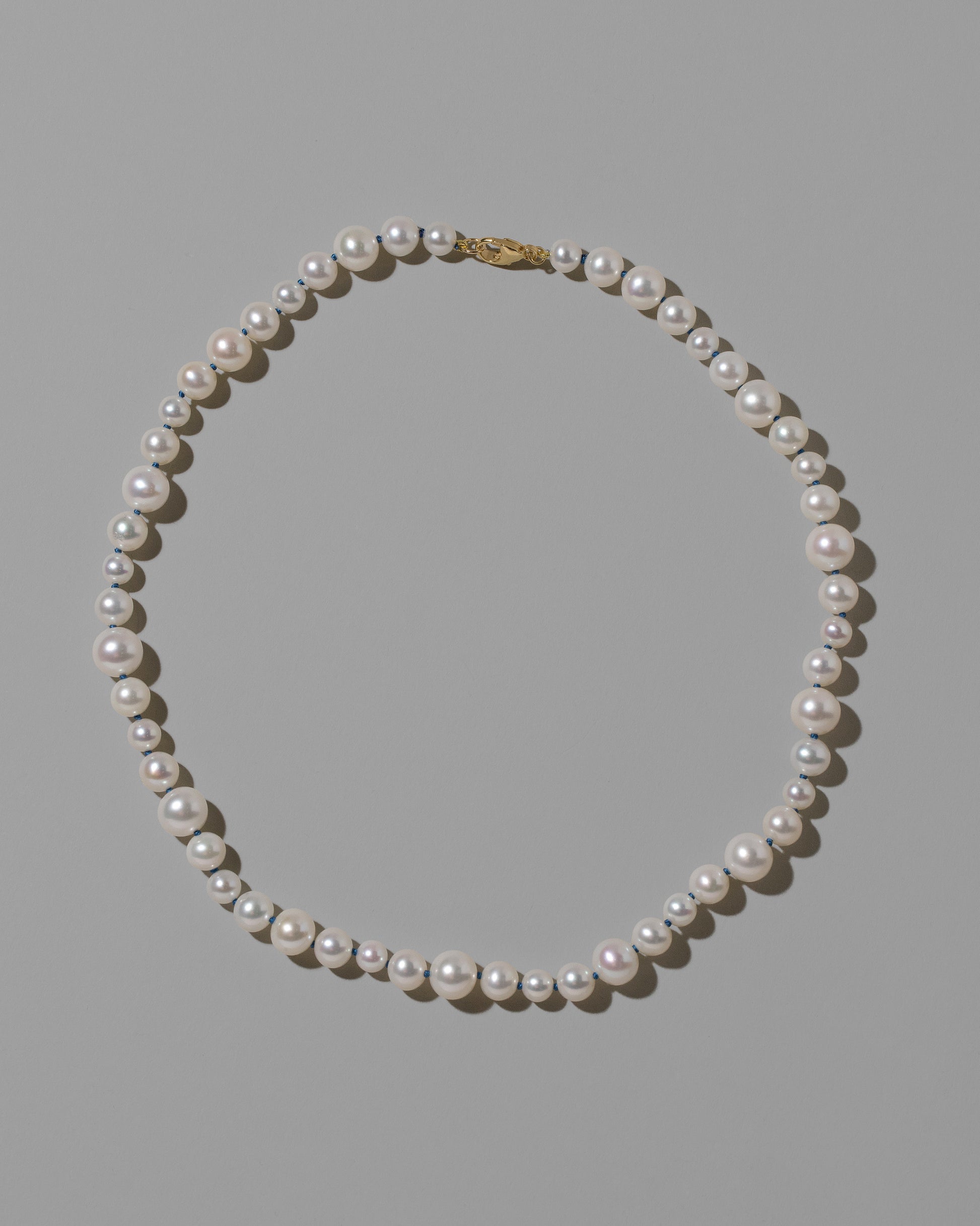 Indigo Thread Bubble Pearl Necklace on light color background.