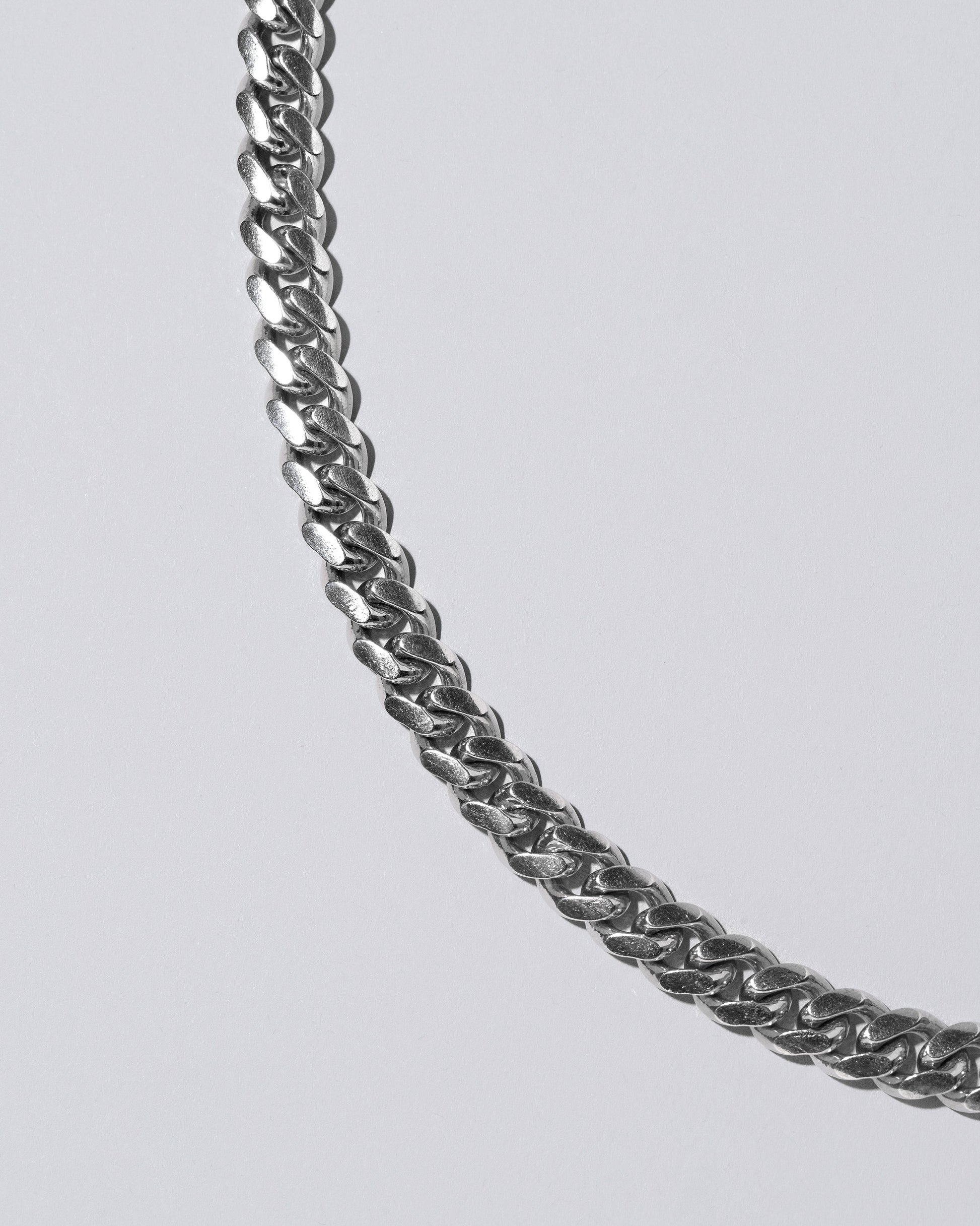 Closeup detail of the Silver Cuban Chain on light color background.