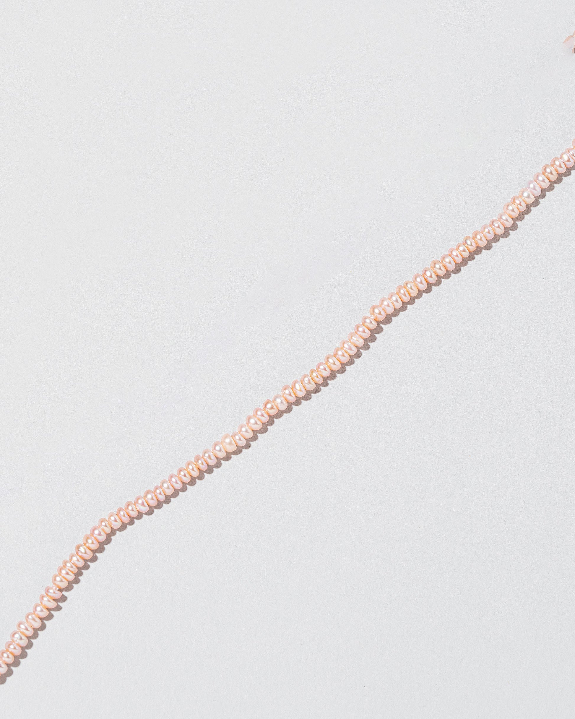 Closeup details of the Pink Peony Seed Pearl Choker on light color background.