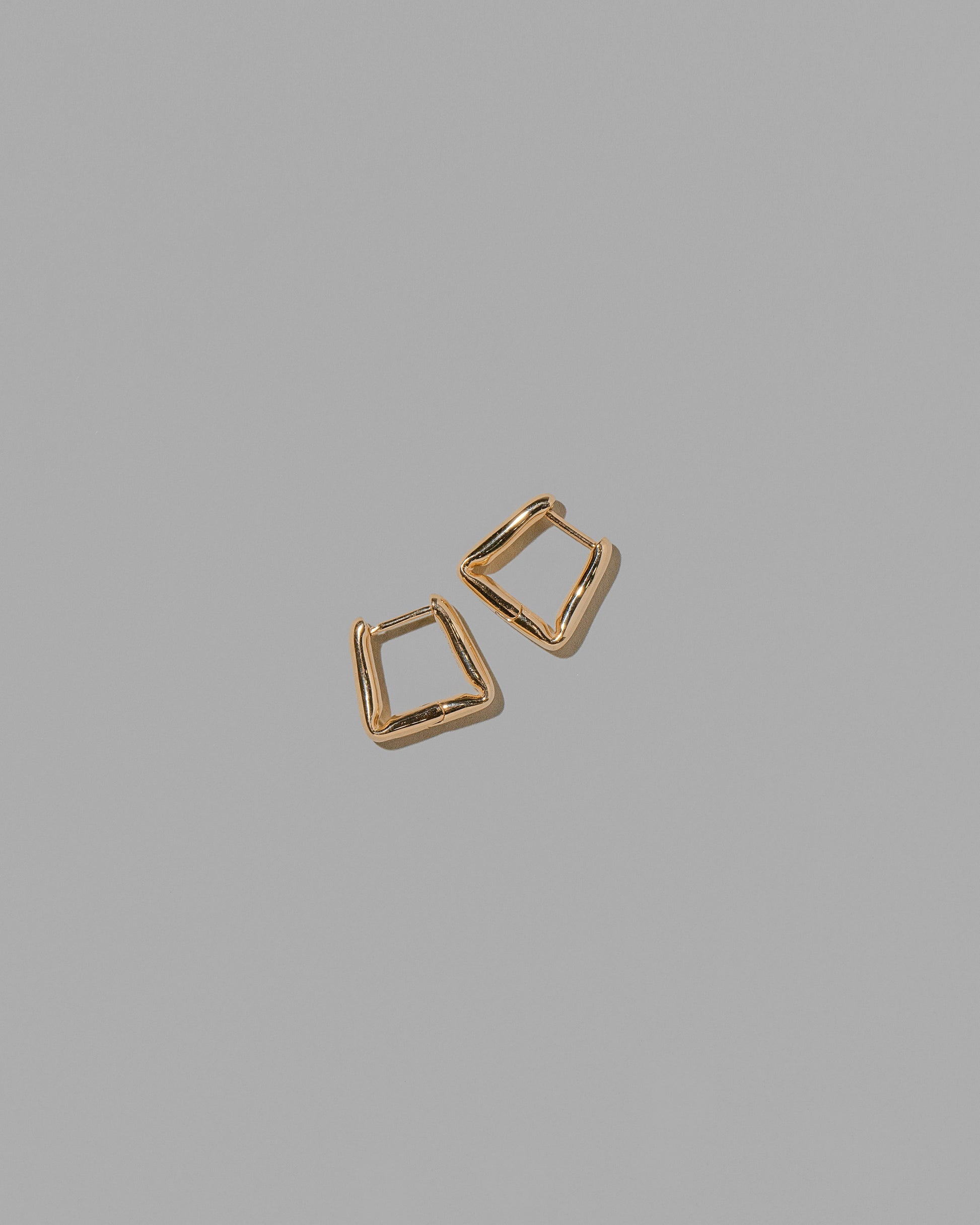 Gold Kink Hoop Earrings on light color background.