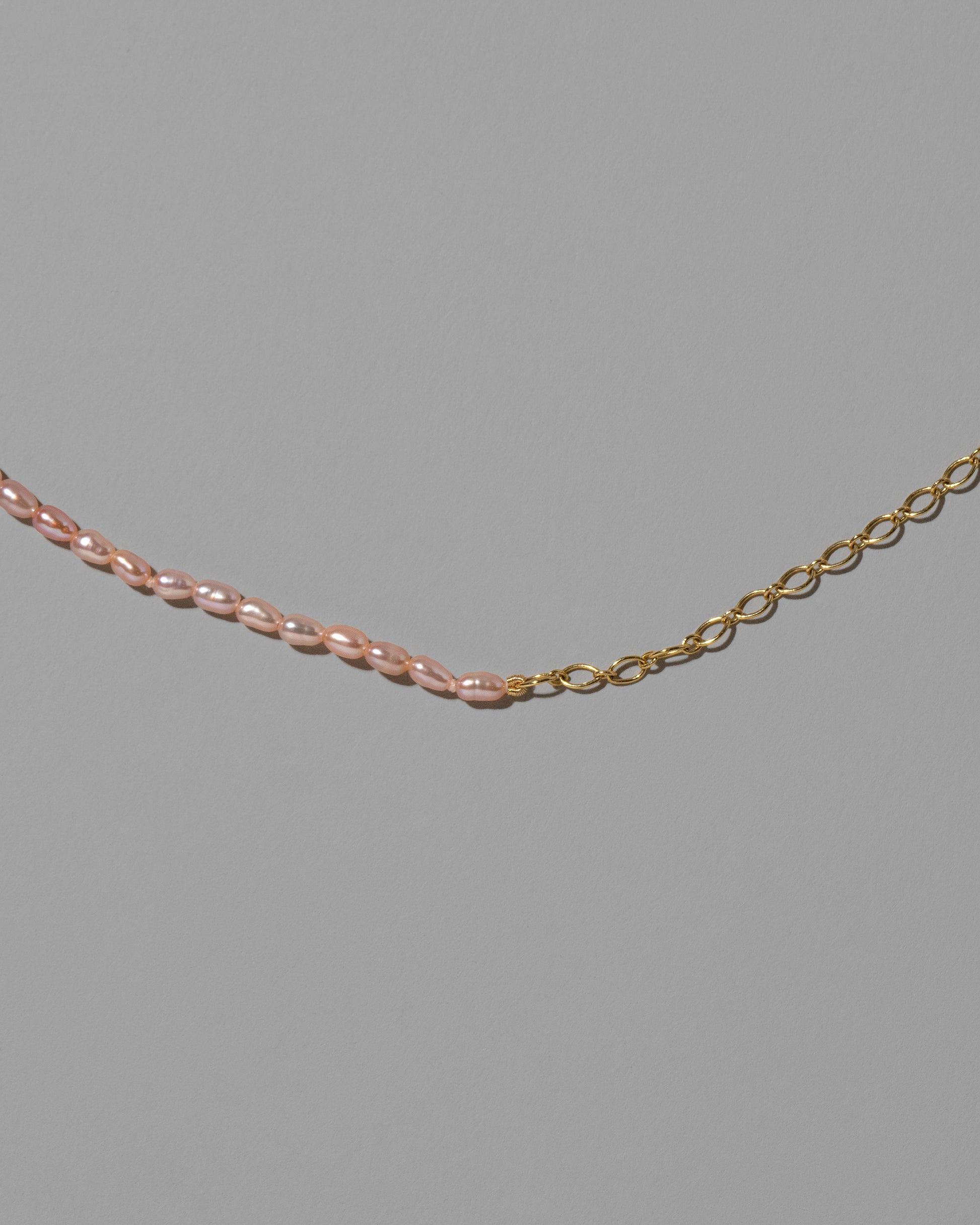 Closeup details of the Half Oval Chain & Peony Seed Pearl Necklace on light color background.