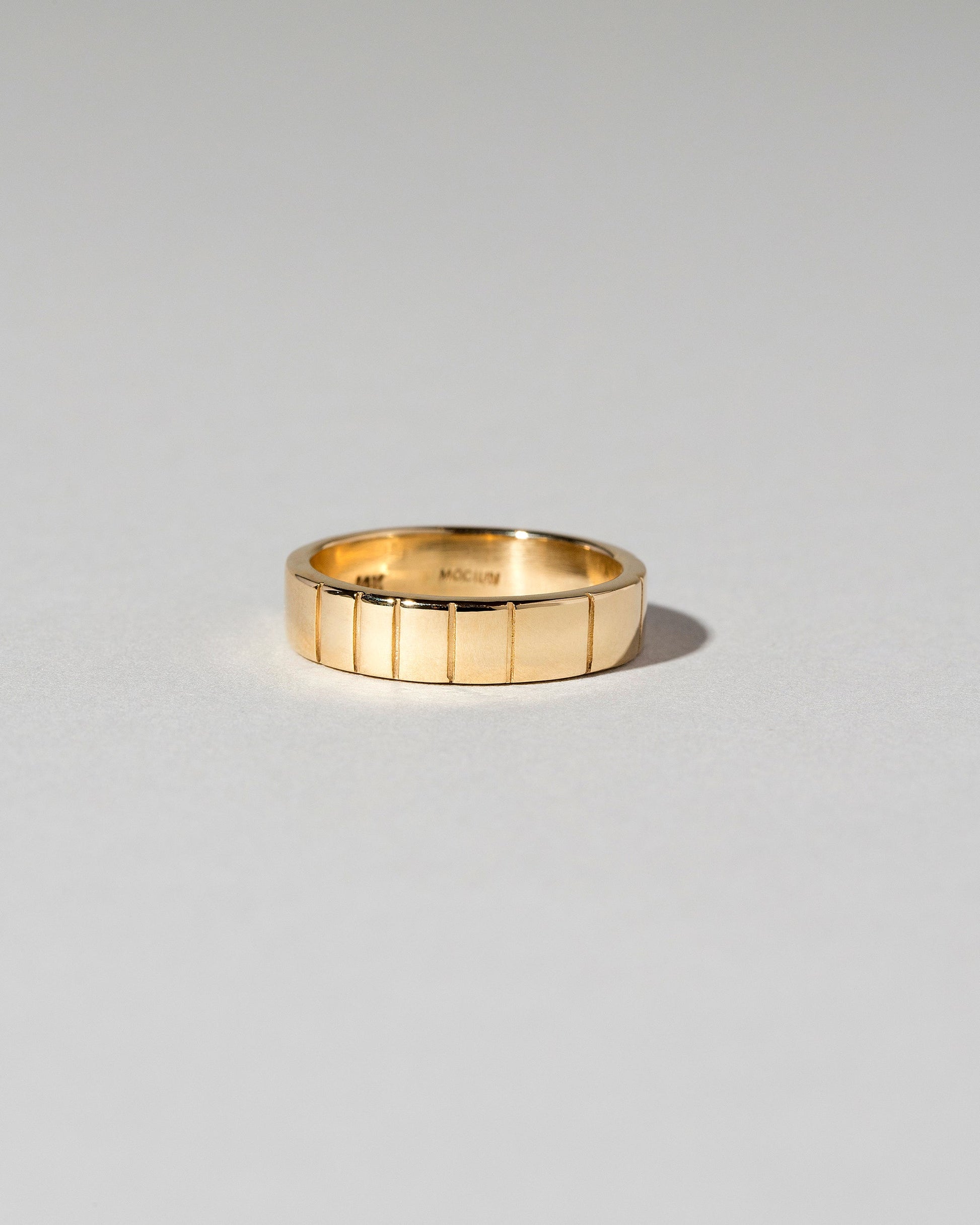 Yellow Gold 6mm Etched Lines Band on light color background.