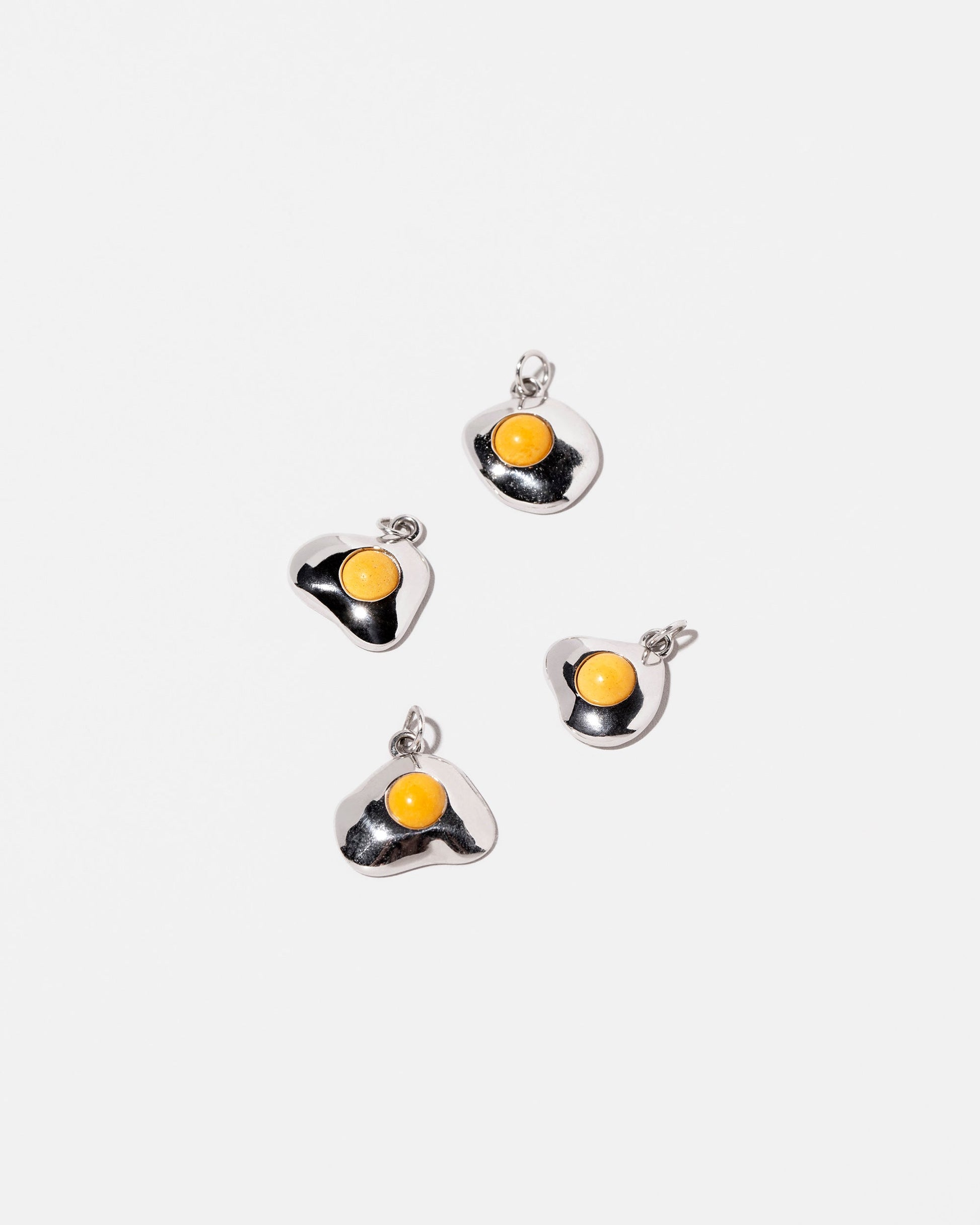 Group of Sunny Side Up Egg Charms on light color background.