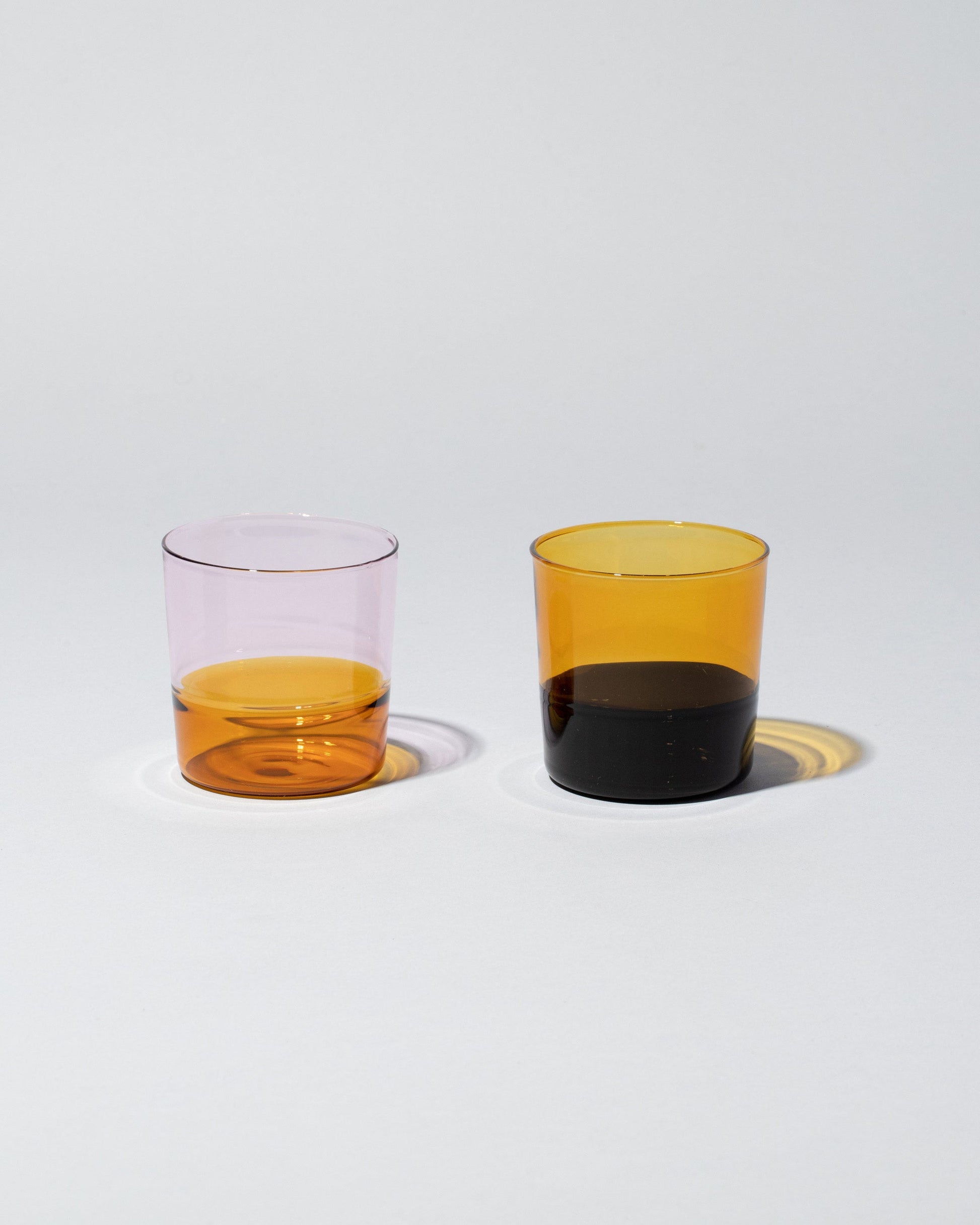 Group of Ichendorf Milano Amber/Pink and Black/Amber Light Colore Water Glasses on light color background.