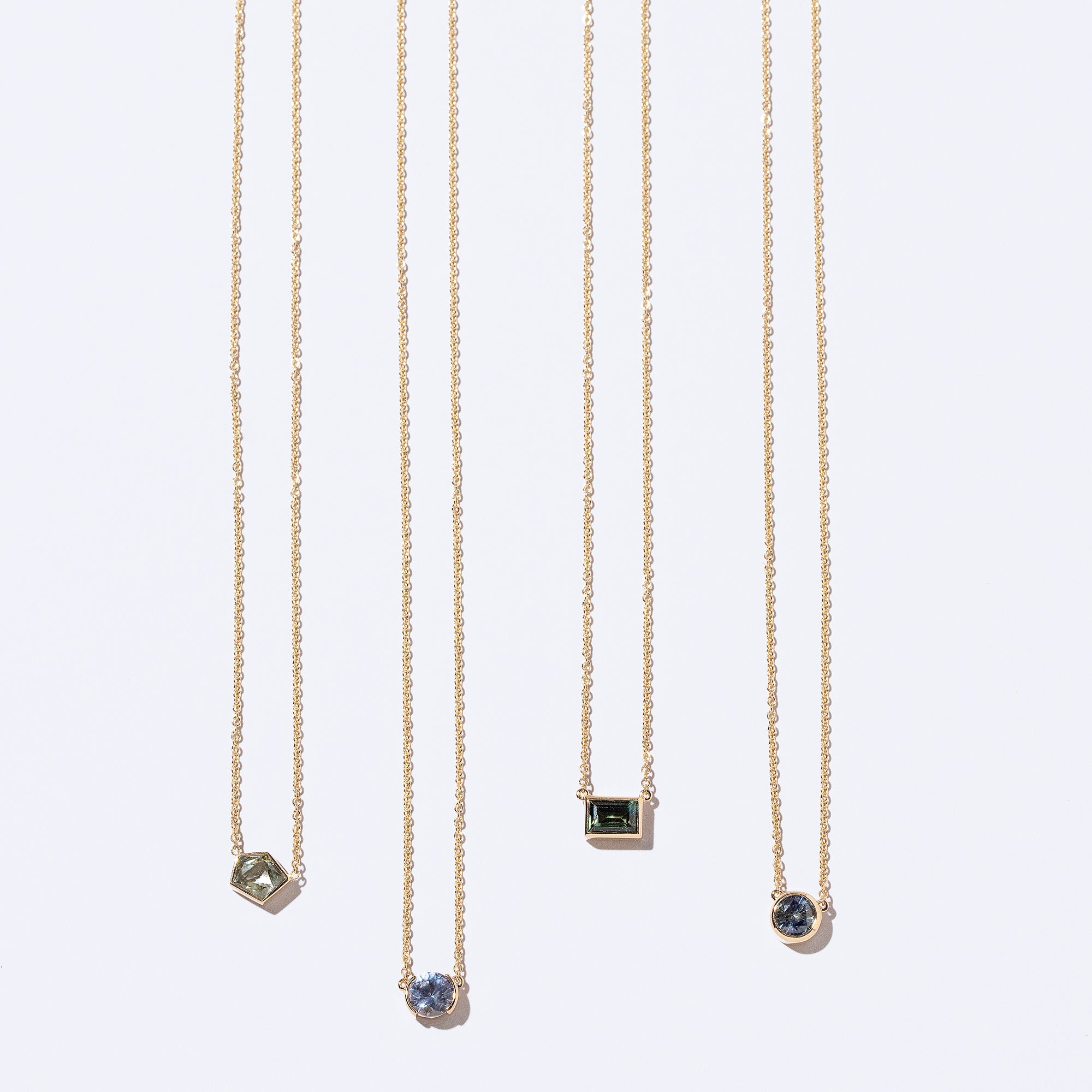 product_details::Geometric Sapphire Necklaces on light colored background.