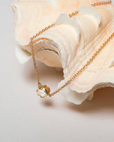 Styled image of the White Diamond Sun & Moon Necklace on light color background.