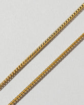 Closeup details of a group of 1.5mm Ritual Chain Necklaces on light color background.