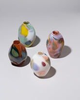 Group of BaleFire Glass Flamingo, White, Orange and Mint Epiphany Diamond Bud Vases on light color background.