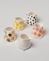 Group of Eleonor Boström Cat Creamers and the Orange, Gold, and Yellow Dog Creamers on light color background.