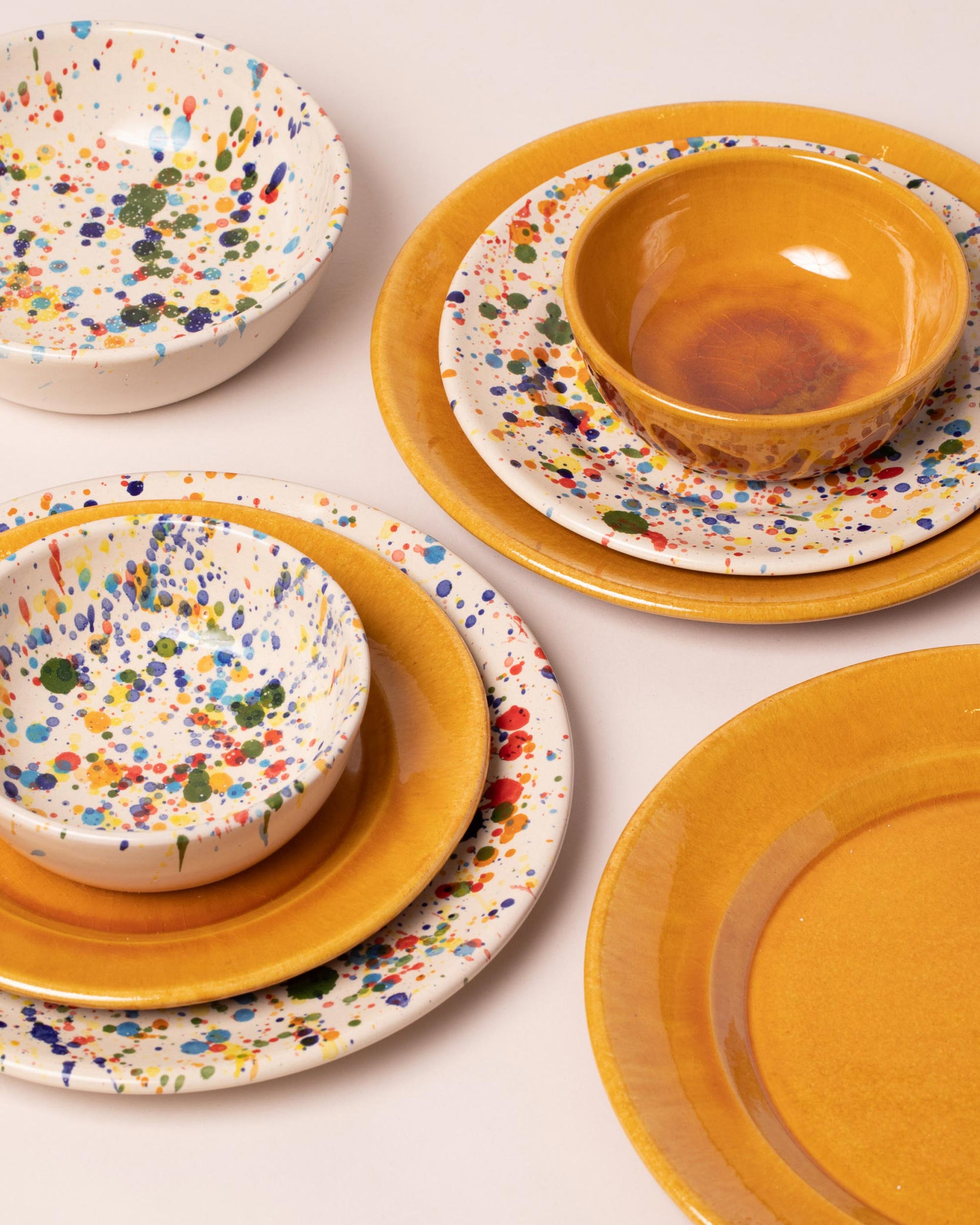 Closeup details of a group of Closeup details of the La Ceramica Vincenzo Del Monaco Caramel Yellow and Colored Drops Dessert Dishes on light color background.